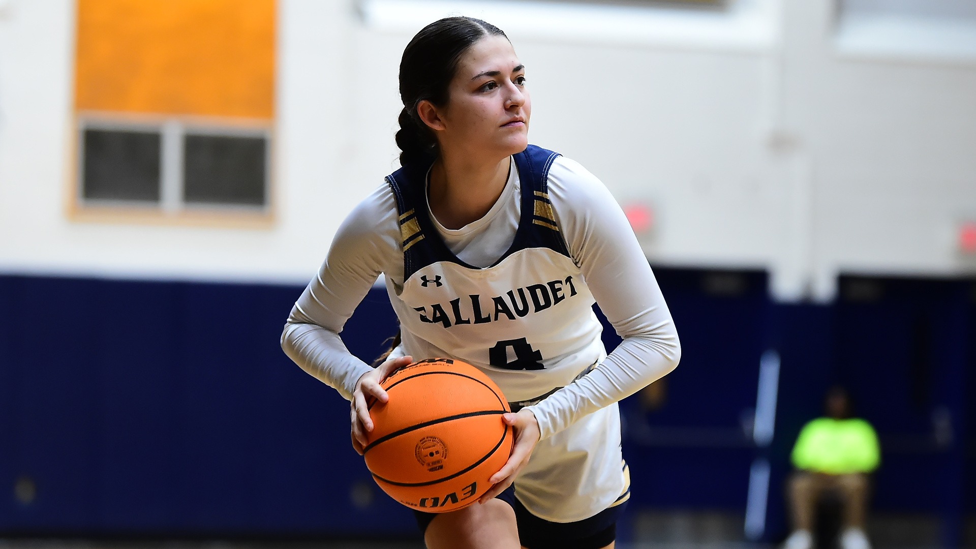 Gallaudet women's basketball player Sunita Schmidjorg attempts to pass as she is reading on the court in close up.
