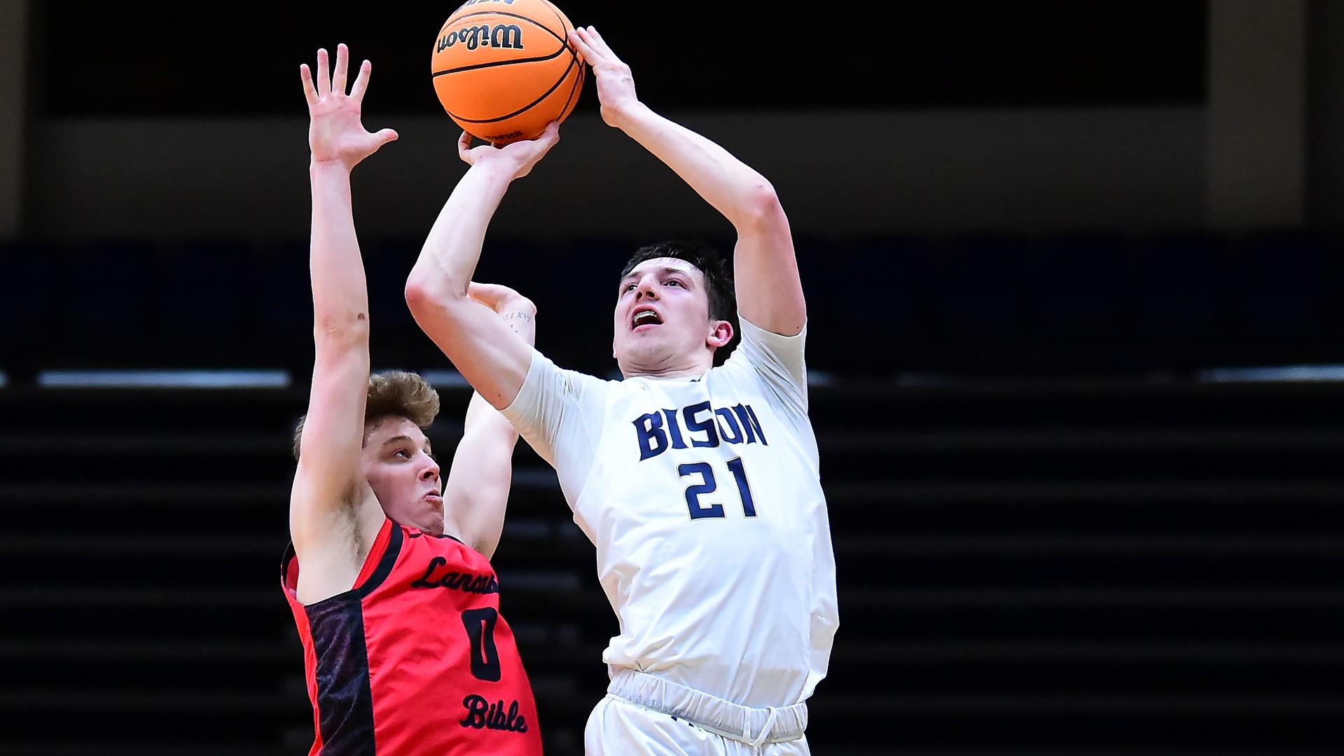 Gallaudet men's basketball player Wyatt Carlson makes a jump shot past a Lancaster Bible College defender in a home game in the Field House. The Bison are wearing their home white uniforms. 