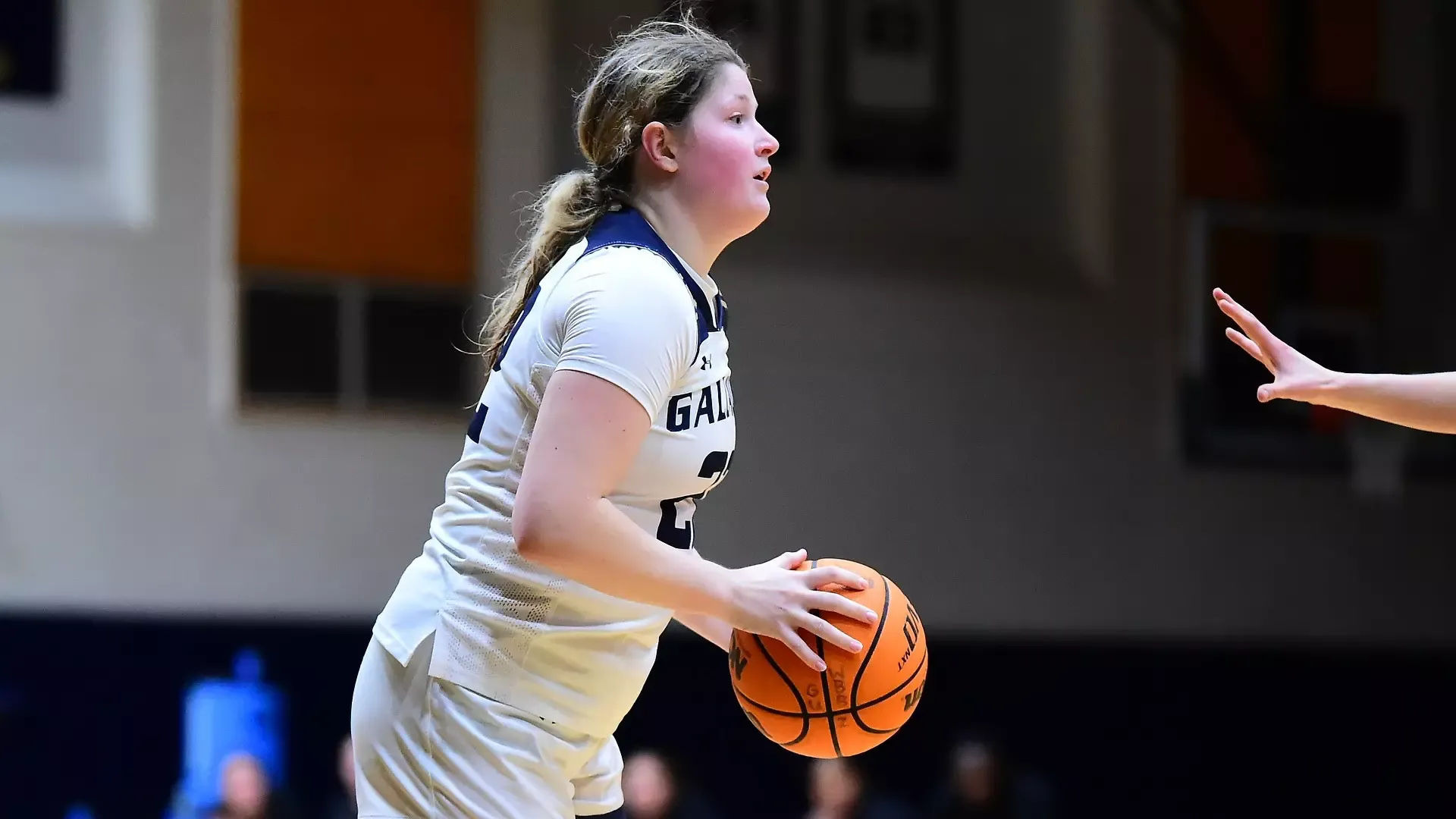 Gallaudet women's basketball player Mackenzie Schirg check the Lancaster Bible College defender before make the pass/shoot during a home game in the Field House. The Bison team is wearing their home white uniforms.