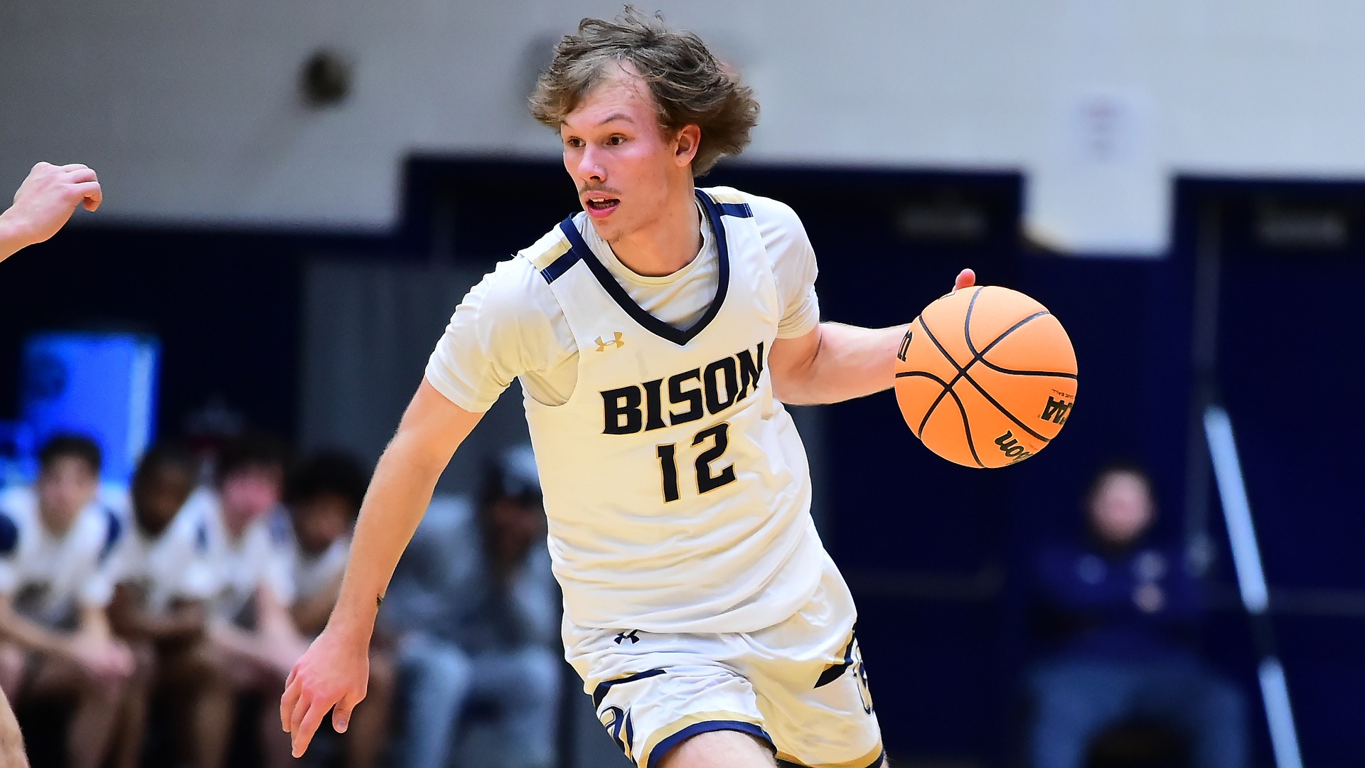 Gallaudet men's basketball player Alex Ortman dribbles an orange basketball up the court. 