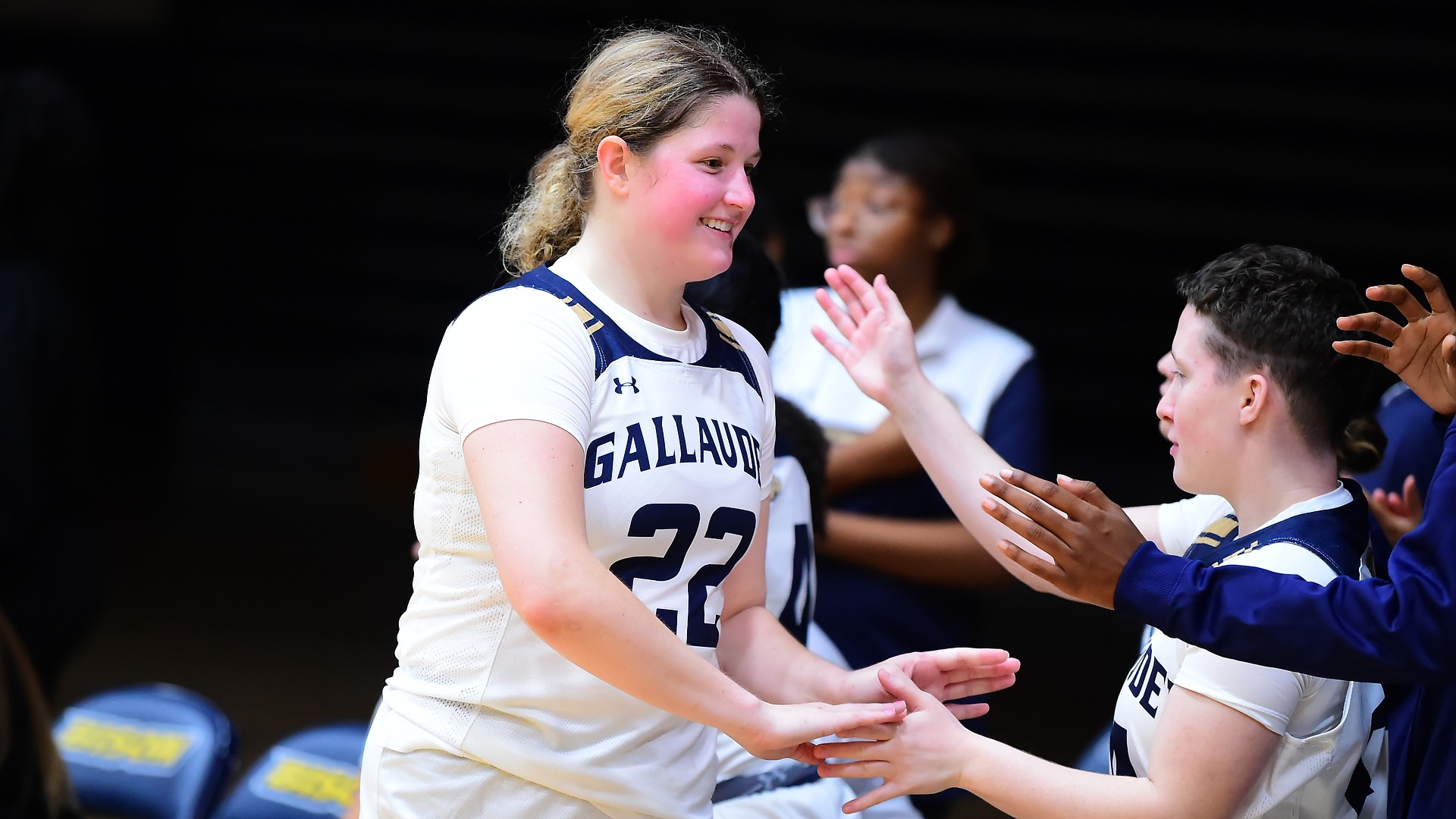 Gallaudet women's basketball players Mackenzie Schirg is having high five with her teammates during a home game in the Field House against Washington Adventist University.