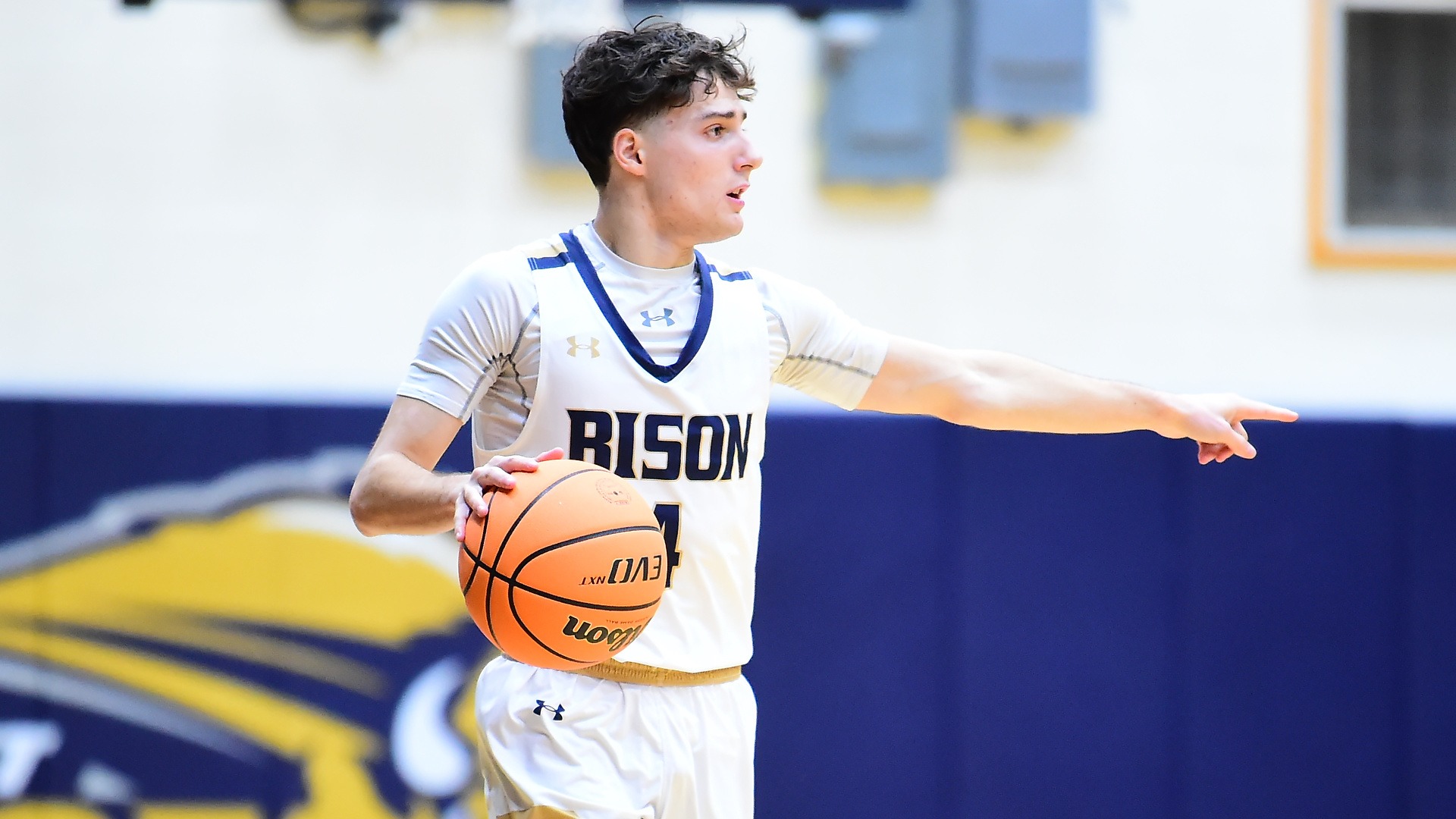 Gallaudet men's basketball guard Kyle Florio helps to direct traffic as he dribbles an orange basketball up the court.