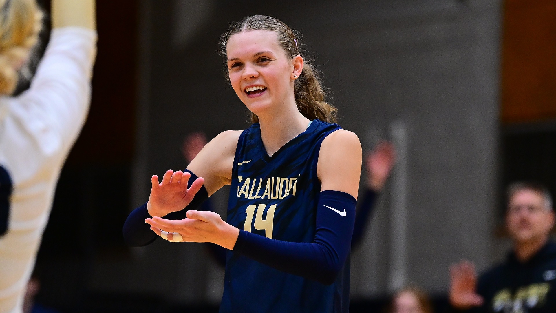 Gallaudet University senior outside hitter Brielle Worley claps her hands after the Bison scored a point in a match. Worley smiles as she looks towards a teammate.