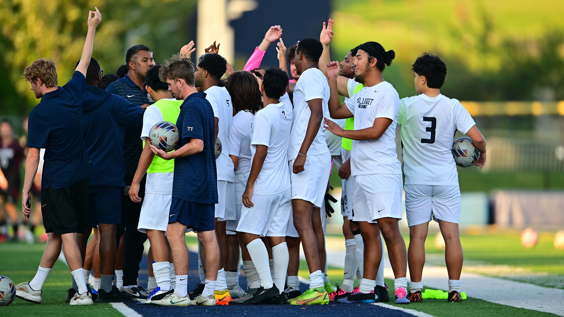 Gallaudet's men's soccer team huddles up at halftime of a game as the sun begins to set on the day. 