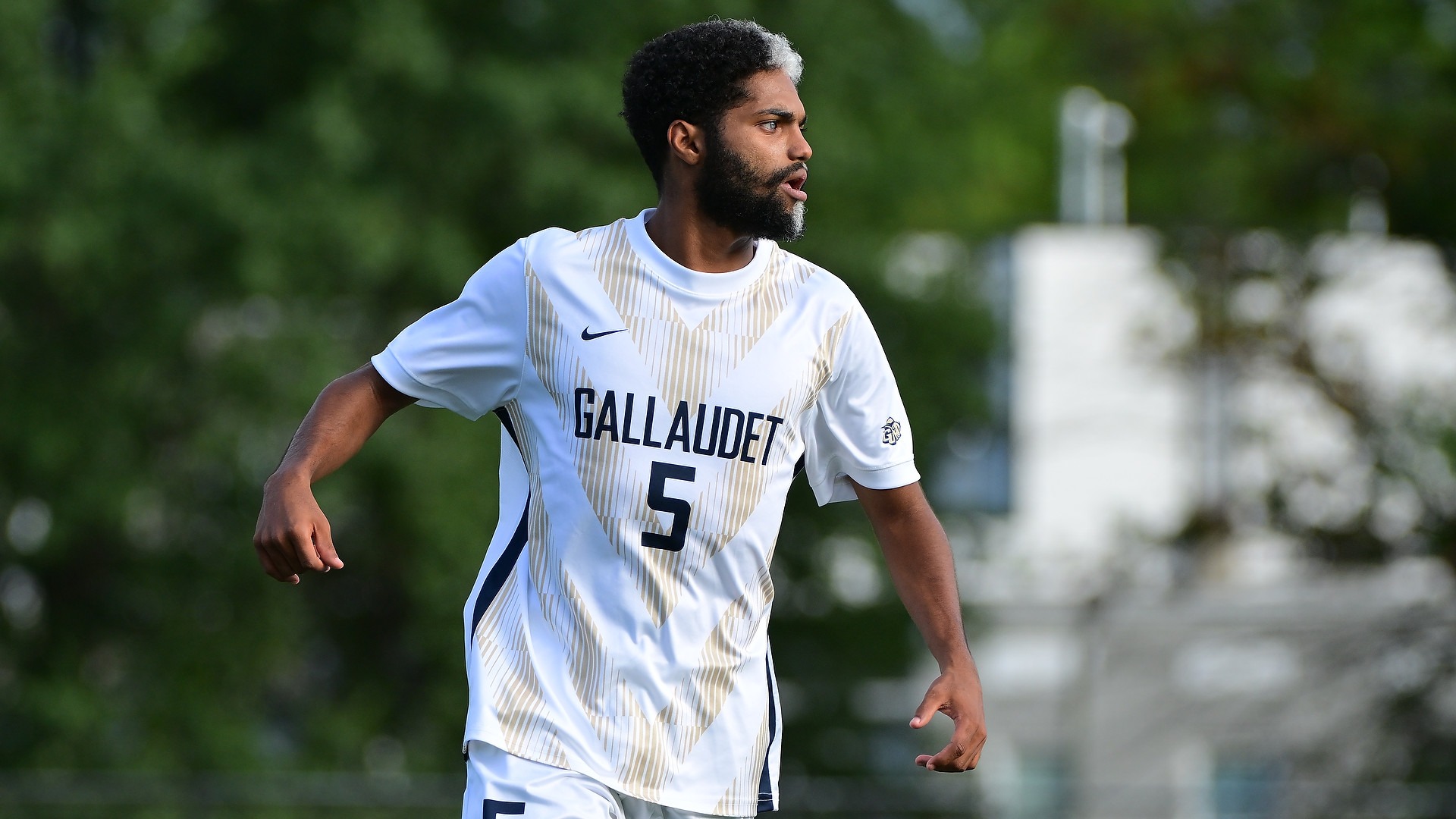 Gallaudet men’s soccer player Bruce Brewer Jr. (#5) looks across the field while moving into position in his white-and-gold Bison uniform during a match at Hotchkiss Field.
