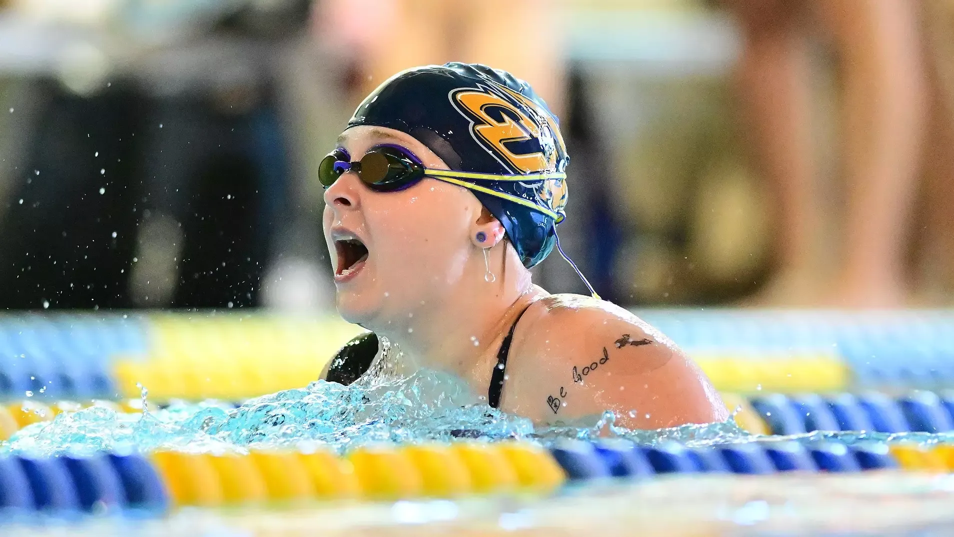 Gallaudet women's swimmer Eliza Peterson performs the breaststroke in the pool during a meet. The photo is cropped tightly on Peterson as she comes up for air.