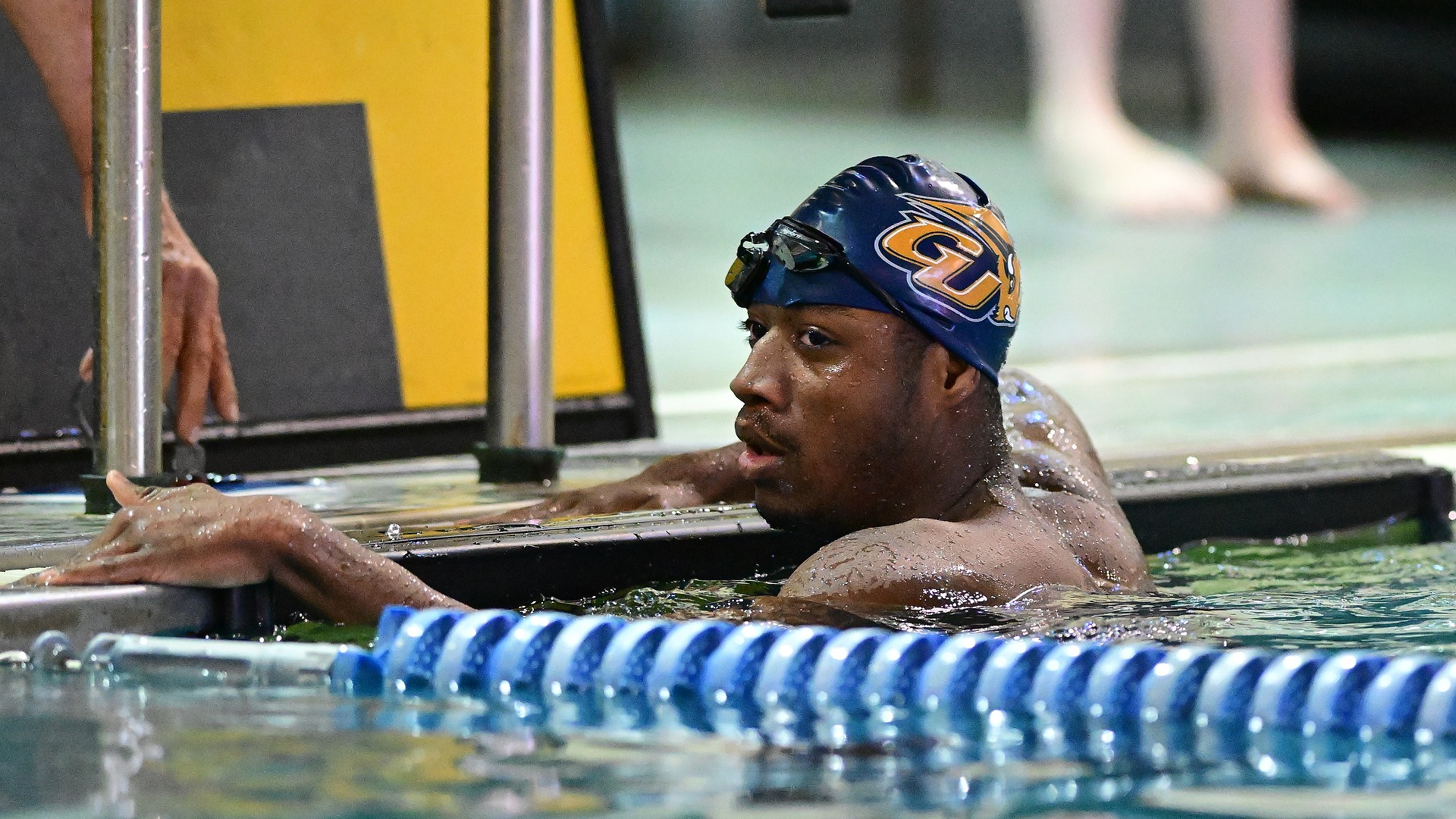 Gallaudet men's swimmer Allen Davis finishes a race in the Field House pool and holds onto the side of the pool and looks over at his coaches.