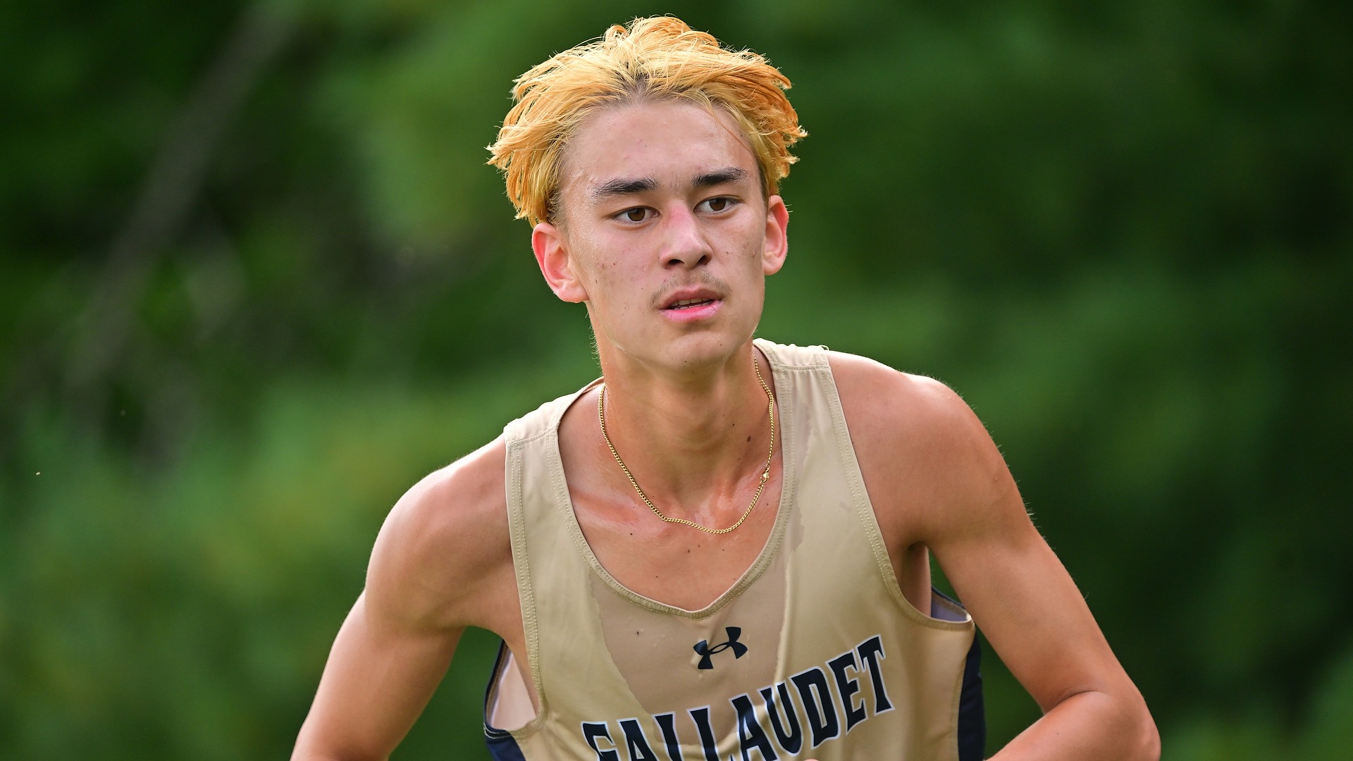 Gallaudet men's cross country runner Sevan Ikeda runs on a sunny day in a cross country meet in close up..