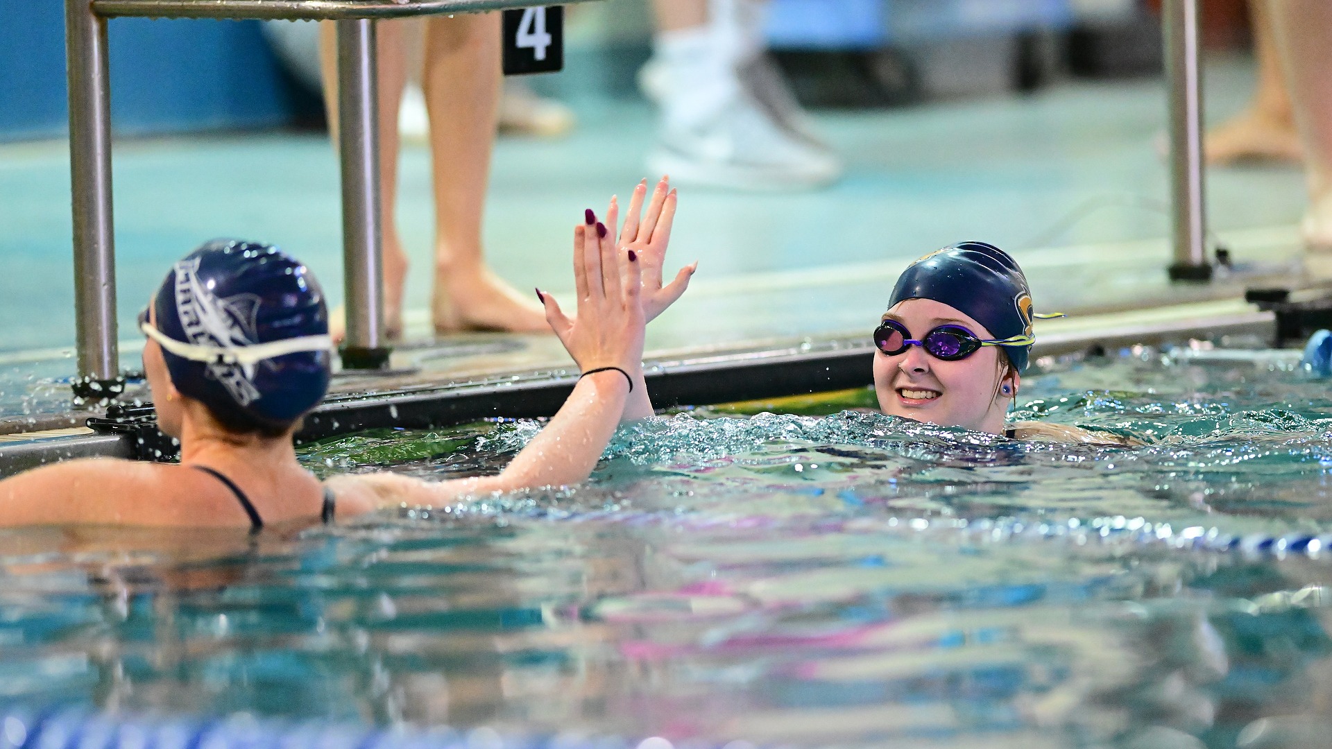 A Gallaudet women's swimmer gives an opponent a high five after finishing an event in the Field House pool.