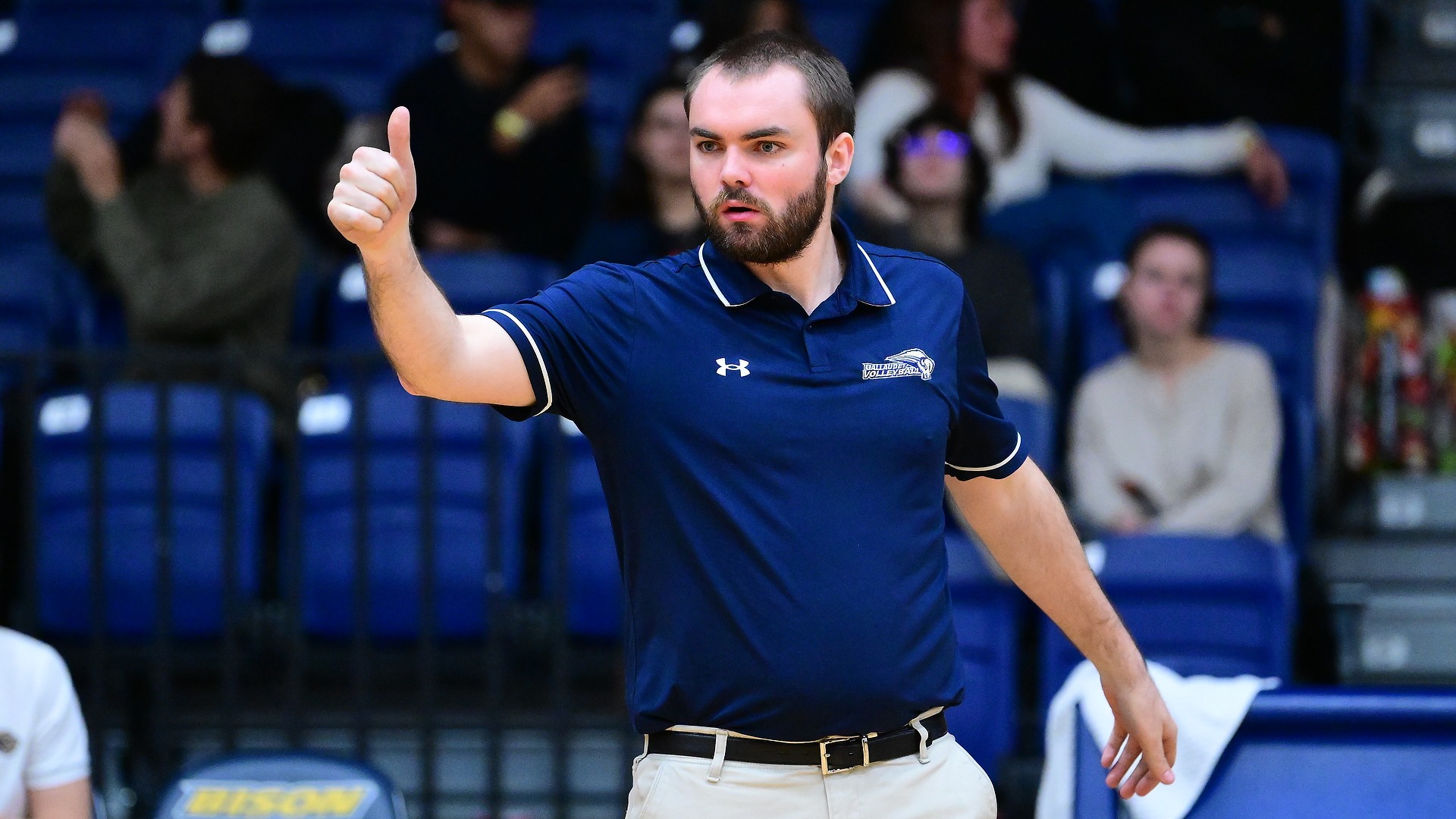 Gallaudet men's volleyball coach Ben Campman gives a thumbs up from the sidelines to his players on the court in the Field House.