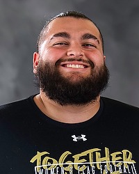 Christian Begani- 2026 Gallaudet women's flag football headshot. The Bison manager wears a black tshirt and looks towards the camera. A gray backdrop is in the background.