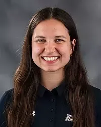 Emelia Beldon- 2026 Gallaudet women's flag football headshot. The Bison coach wears a black polo shirt and looks towards the camera. A gray backdrop is in the background.