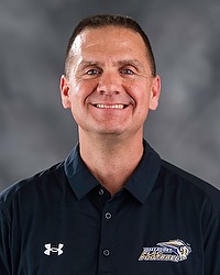 Tony Ortiz- 2026 Gallaudet women's flag football headshot. The Bison coach wears a black polo shirt and looks towards the camera. A gray backdrop is in the background.