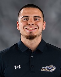 Zion Ortiz- 2026 Gallaudet women's flag football headshot. The Bison coach wears a black polo shirt and looks towards the camera. A gray backdrop is in the background.