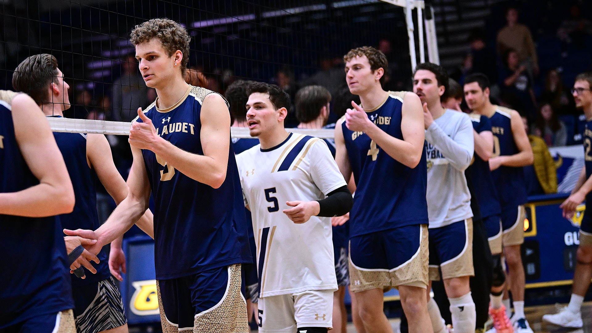 Gallaudet men's volleyball players shake hands after a match in the Field House and sign good game to the opponent.
