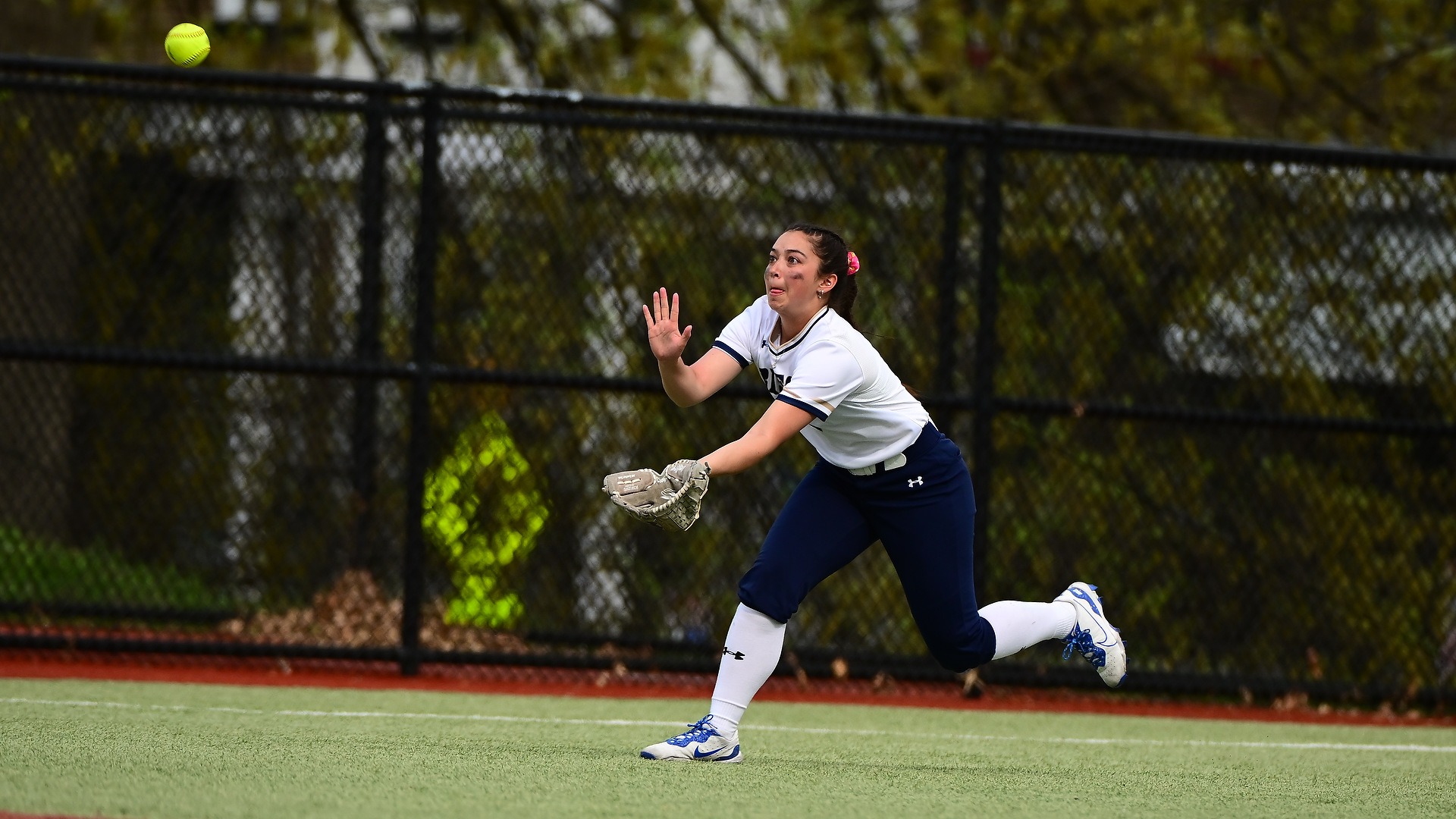 Gallaudet softball player Sammie Howell runs in from the outfield to make a catch on a sunny afternoon day.