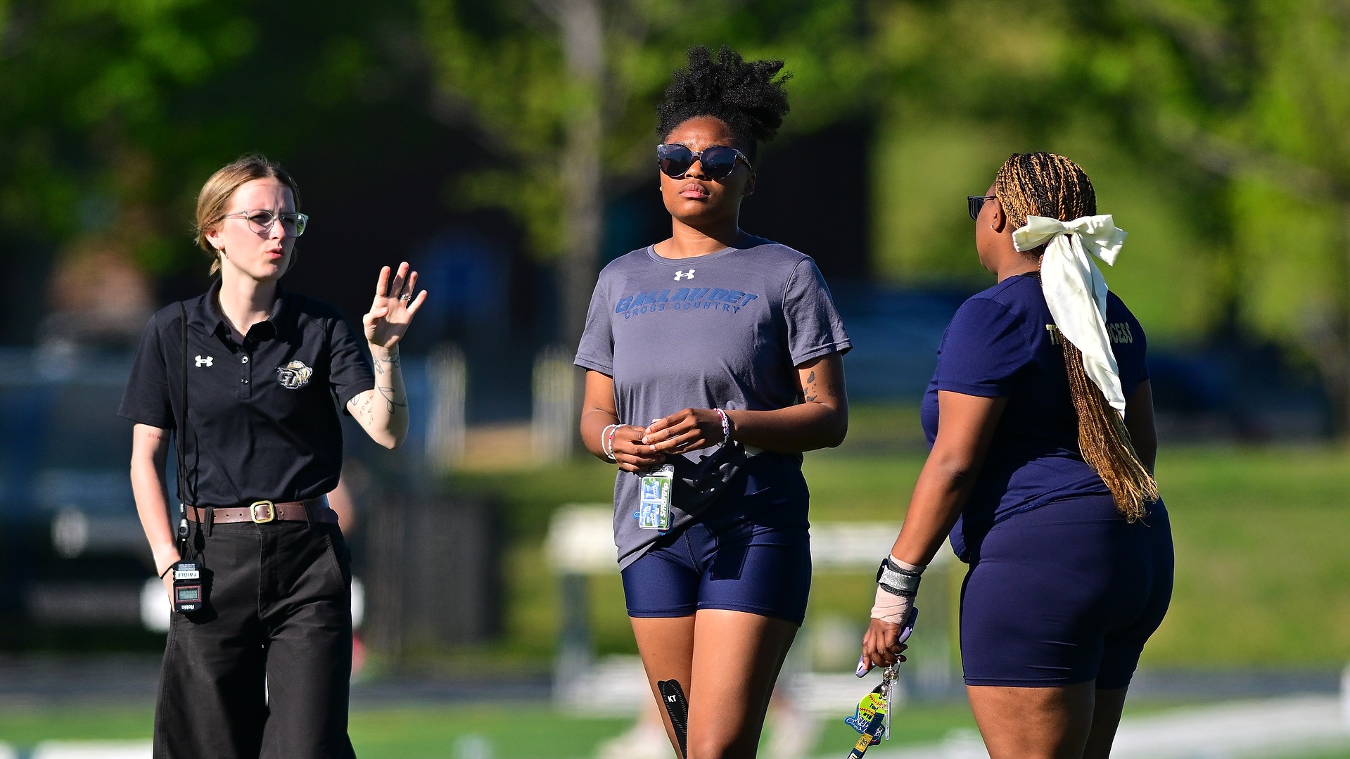 Gallaudet women's track and field members take a stroll through the infield on a sunny afternoon. Pictured in the middle is Jala Furdge and on the right is teammate Tori Cushshon. Assistant coach Nykol Pratt is on the left.