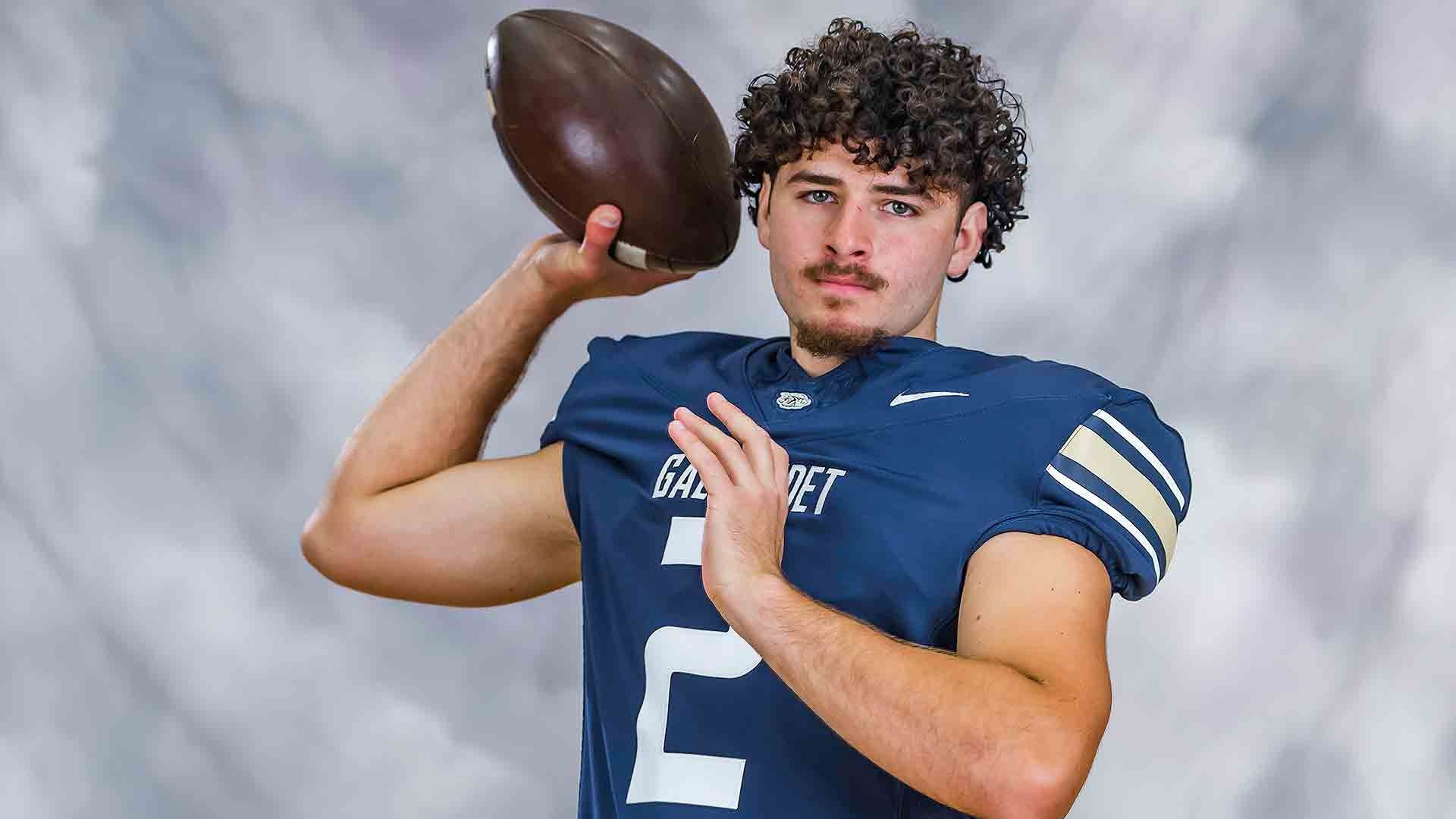 Gallaudet quarterback Jayden DeFalco (#2) poses in his navy blue Bison uniform with his right arm raised and a football in hand, preparing to throw.