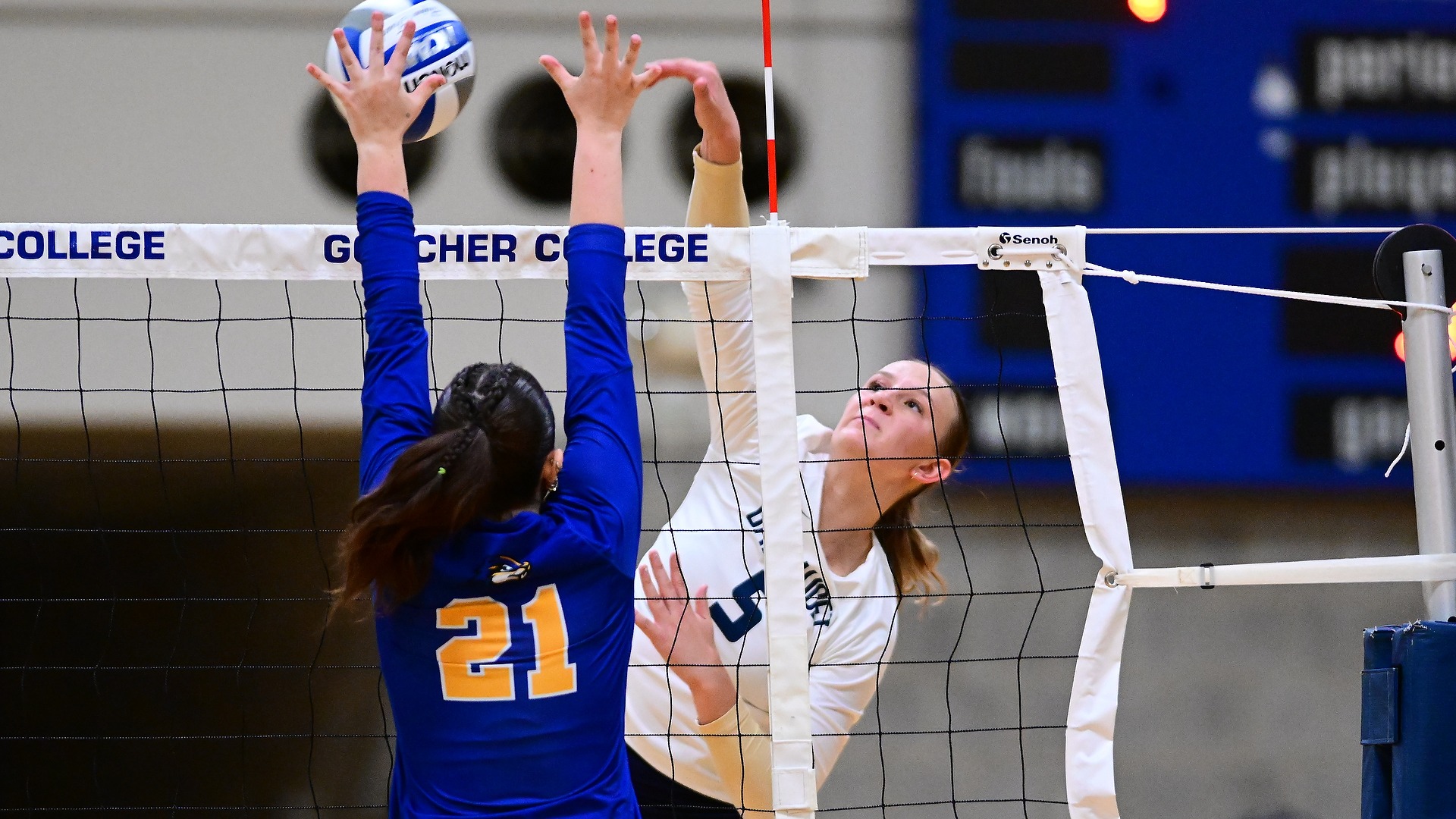 Gallaudet women’s volleyball player Jada Zarembka (#5), wearing a white Bison uniform, reaches high to attack the ball over the net against a Goucher College blocker Juliana Stoneberg (#21) during the Bison’s road match on Sept. 17.