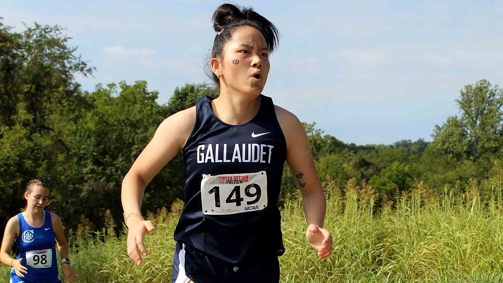 Gallaudet women’s cross country runner Xue Atwood, wearing a navy Bison singlet and bib No. 149, competes along a grassy course on a sunny Saturday morning at the South Region Preview in Earlysville, Virginia.