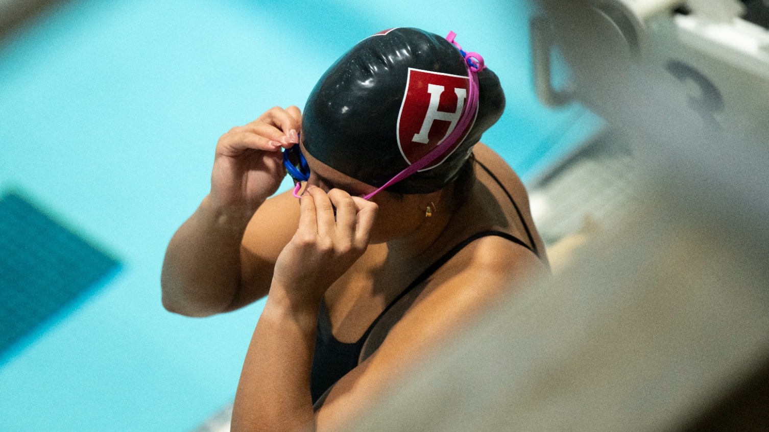 Women's swimmer adjusting goggles