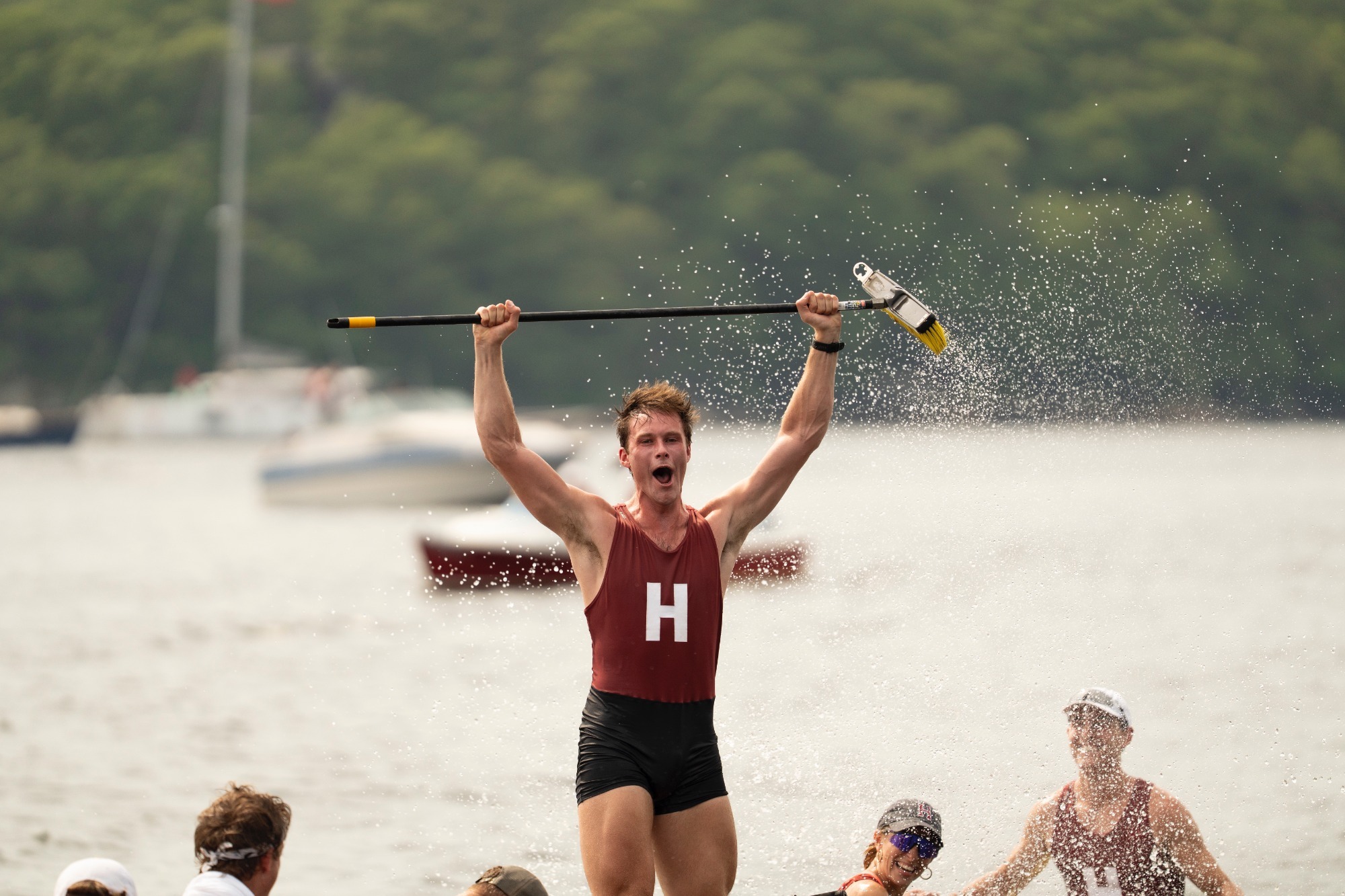 Jack Dorney holds a broom above his head after Harvard sweeps Yale.