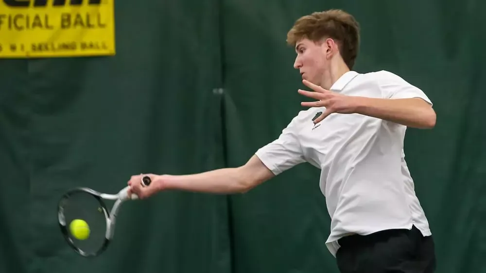 This is an action shot of Yurii Hoida from the Chicago State Men's Tennis team at a home match where he is hitting a tennis ball