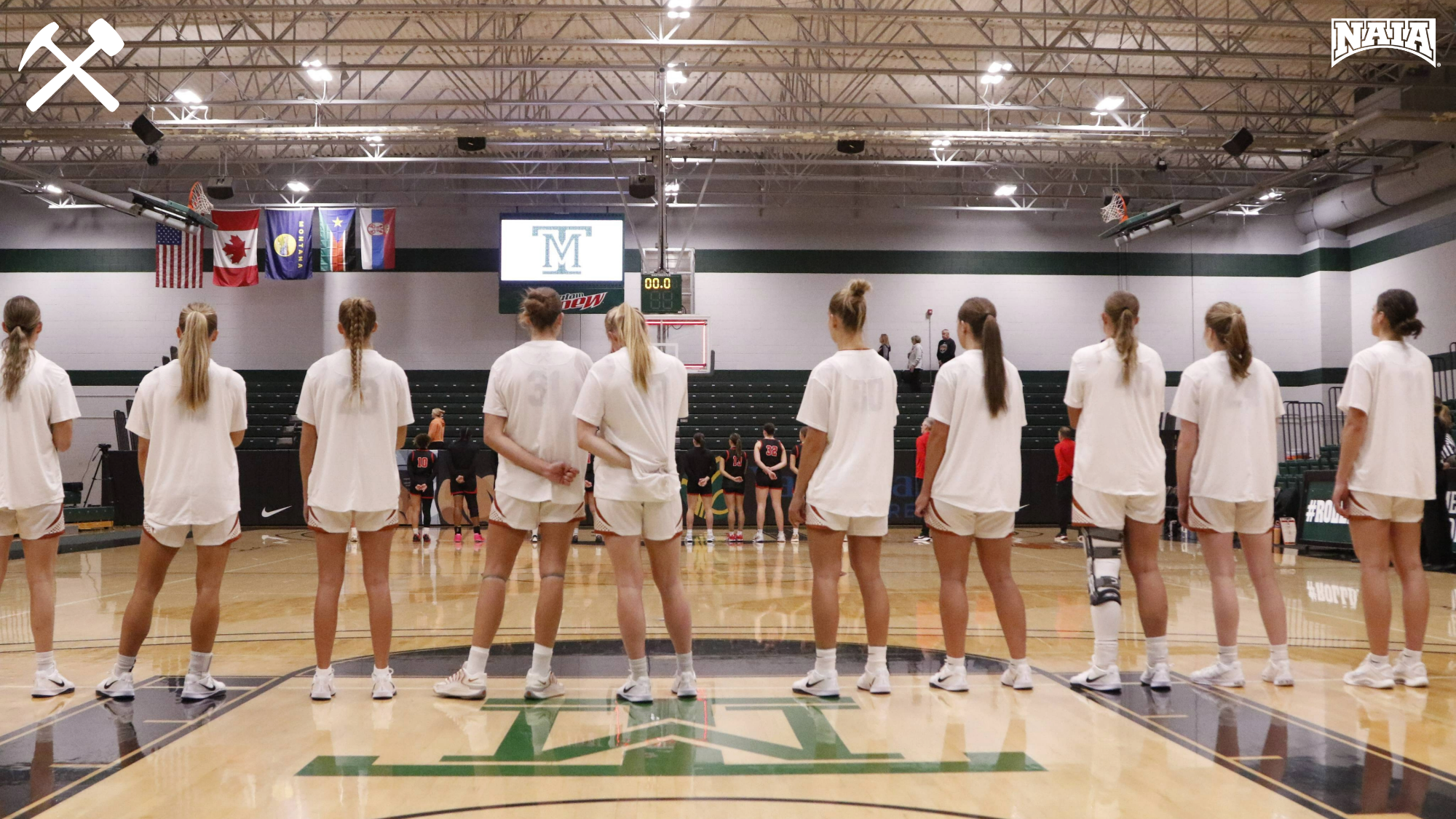 Montana Tech women's basketball players face the flag for the national anthem prior to a home game
