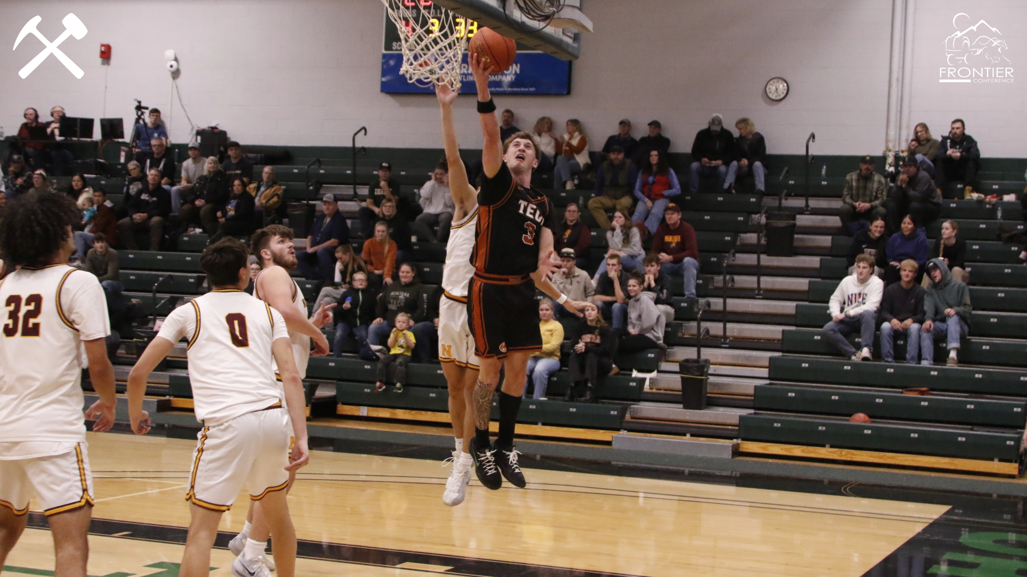Brayden Koch lays the ball in the basket around an MSU-Northern defender during a Montana Tech men's basketball game