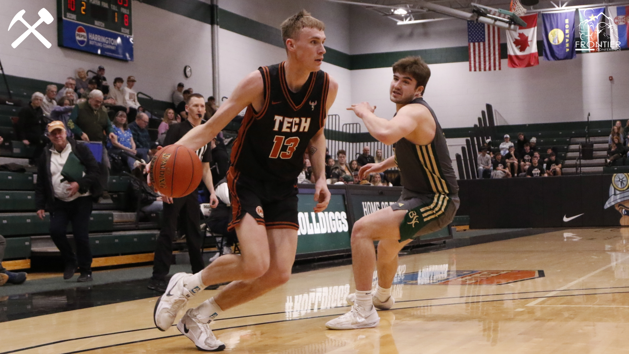Eli Quinn dribbles the basketball by a defender during a Montana Tech men's game