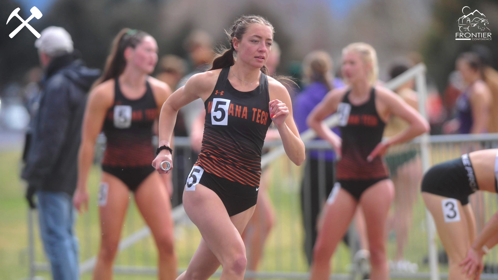 Kam Comba running in a relay during a track meet