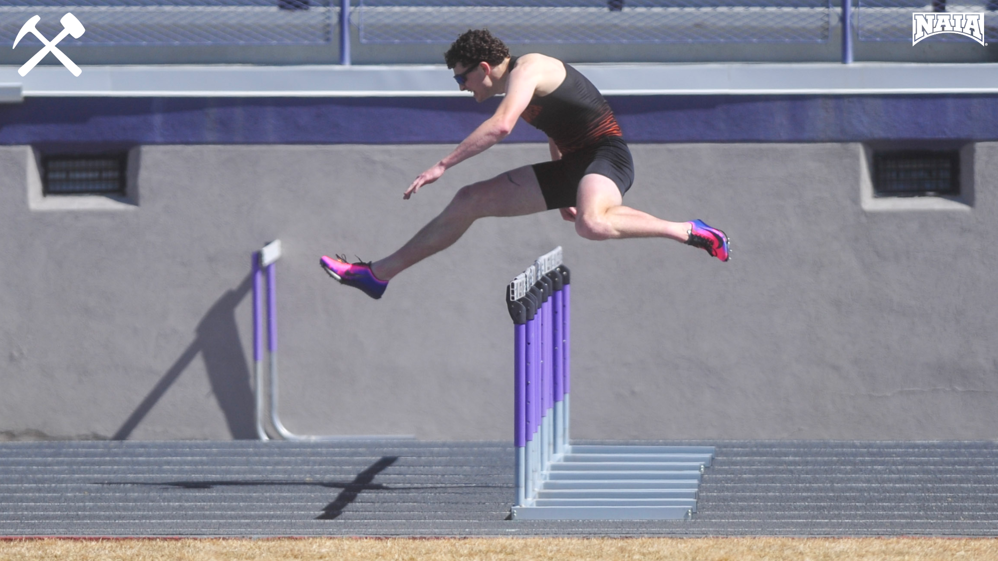 Side angle of Morgan McClernan clearing a hurdle in a track race