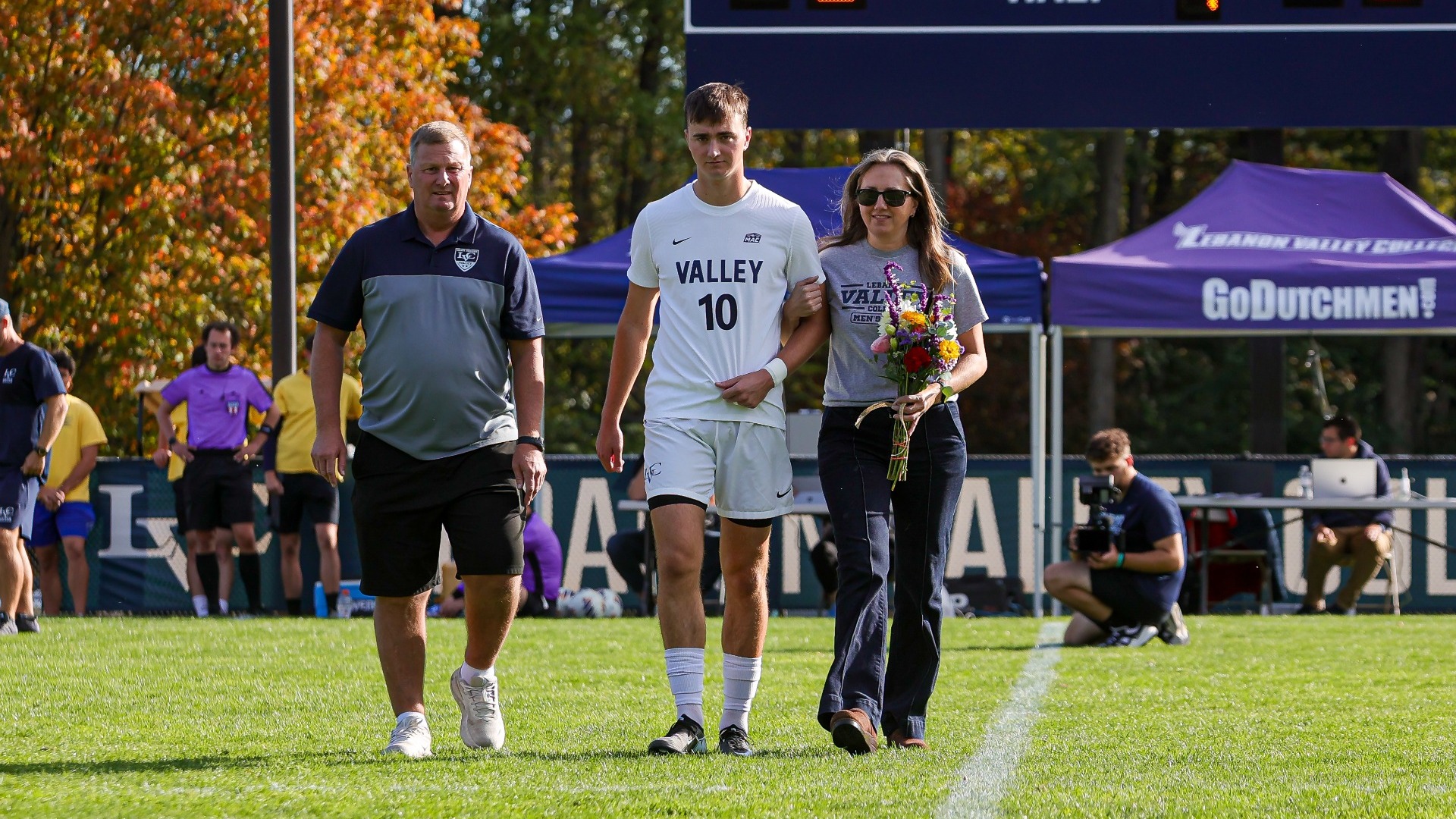 Nathan Prex walking with parents on Senior Day