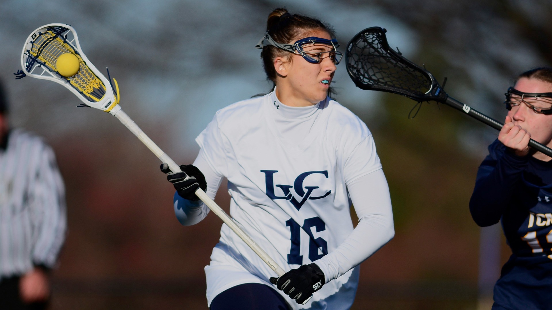 Kyla Hebert holding ball in stick running away from defenders