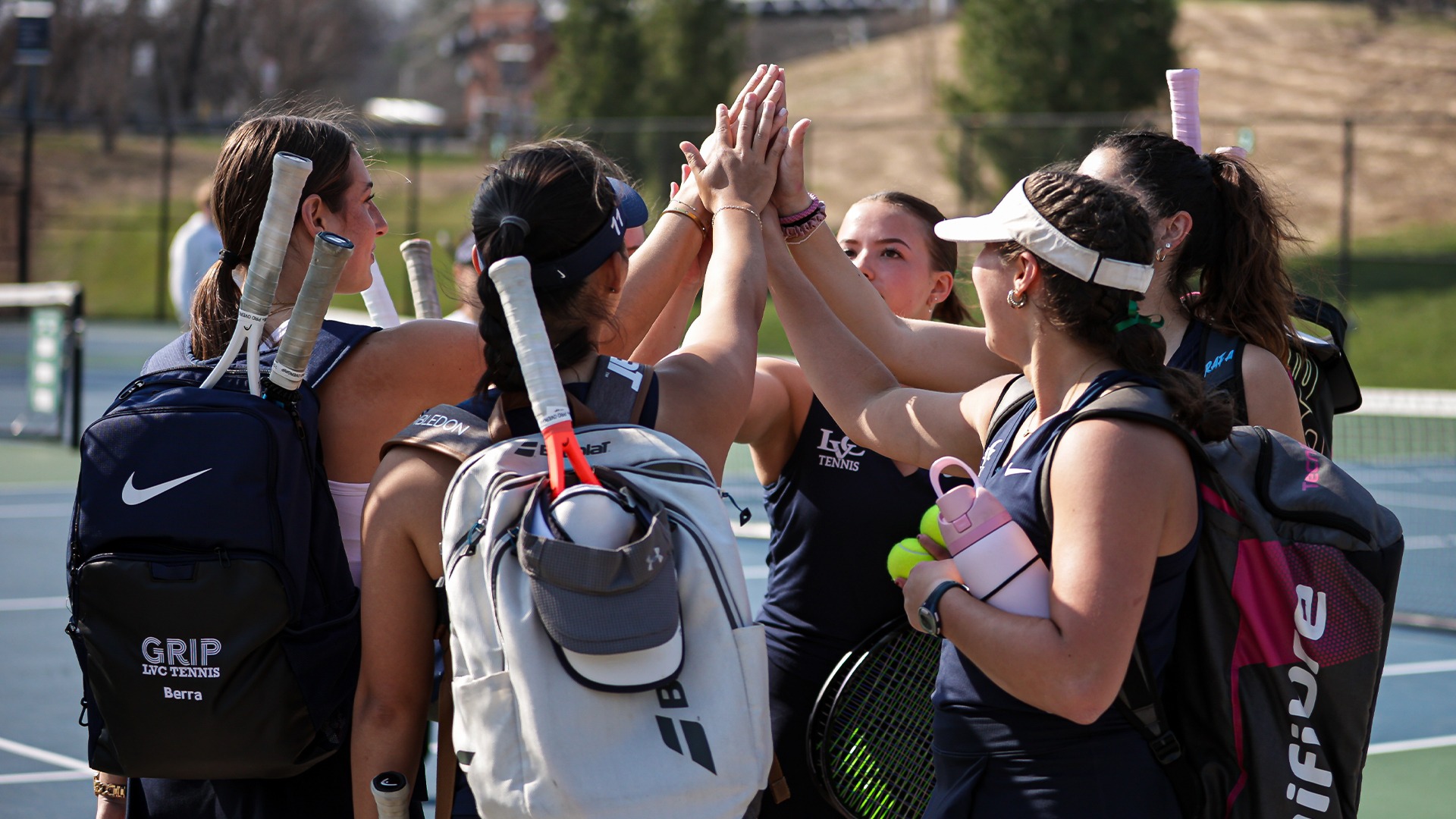 Women's tennis team huddled together for pre-match cheer