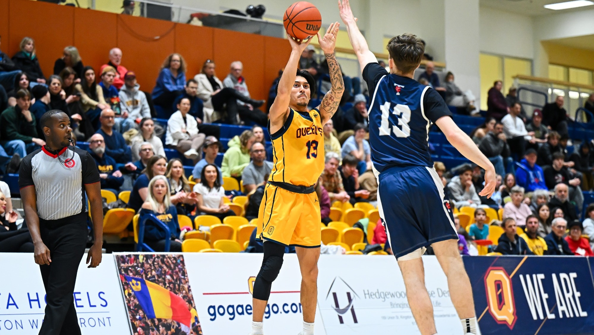 Queens' Men's Basketball's Noah Khaja shoots the basketball with a Toronto Varsity Blues player defending