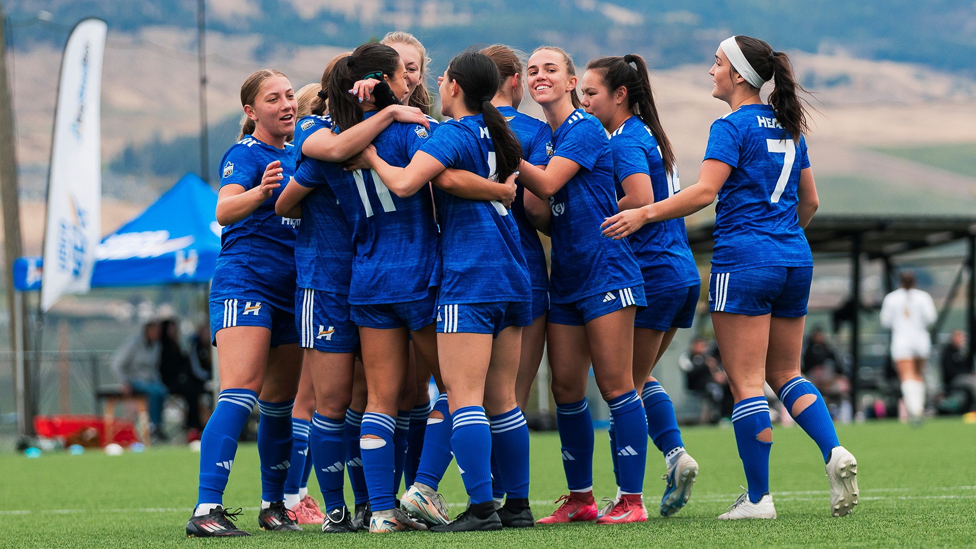The UBCO Heat women's soccer team swarm goal scorer Maria Georgacacos after her opening goal against the UNBC Timberwolves at Nonis Sports Field.