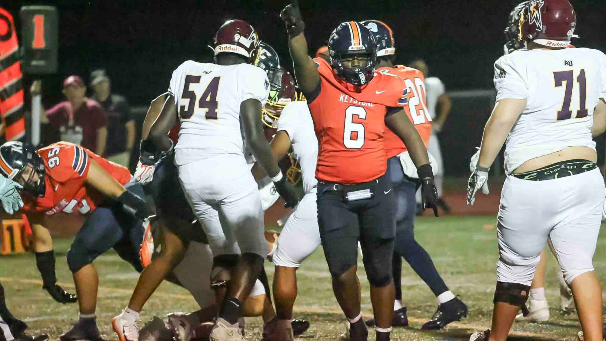 Keystone football player #6 celebrates after a play as teammates and Alvernia players gather around the tackle during the Giants' Week 1 game.