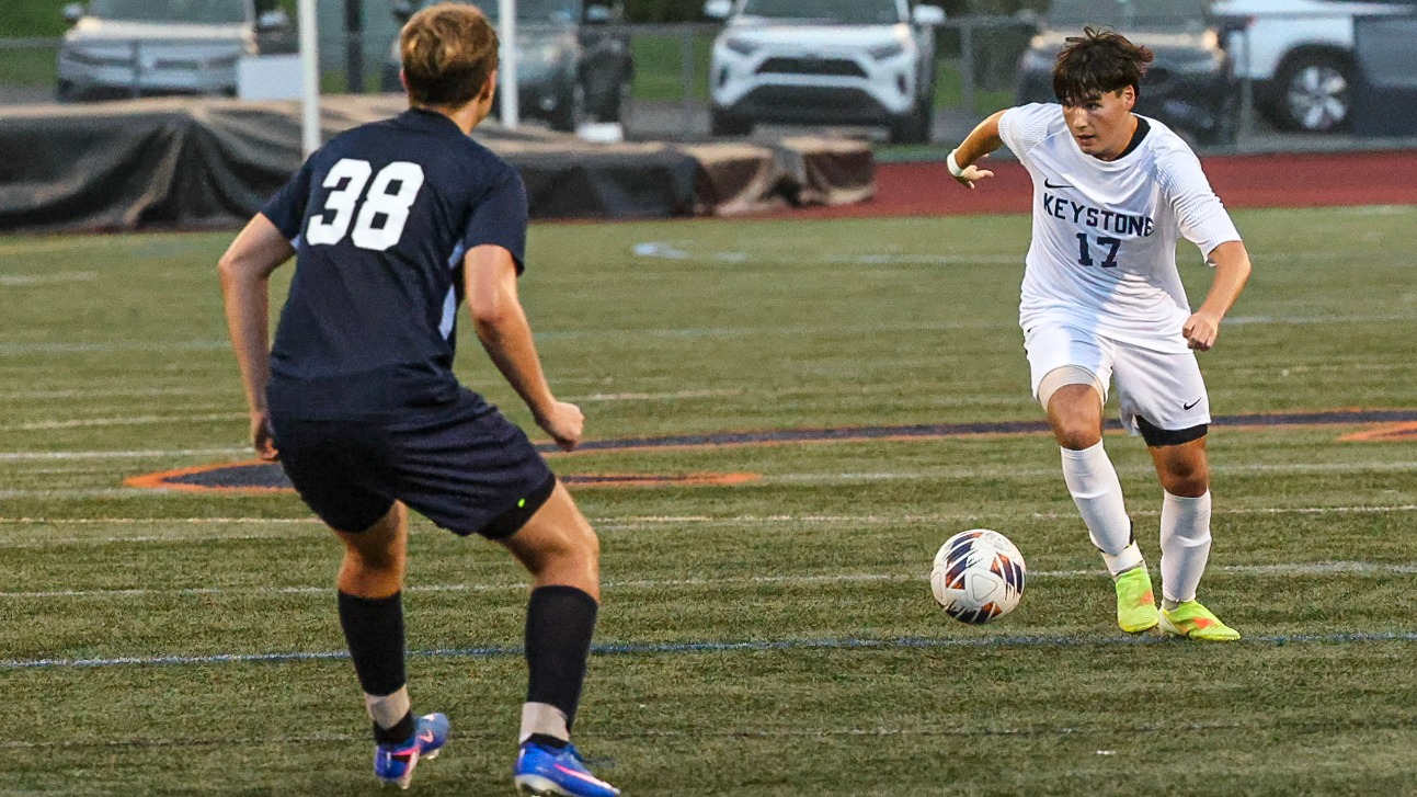 Keystone men’s soccer player No. 17 dribbles the ball upfield against an opposing player wearing No. 38.