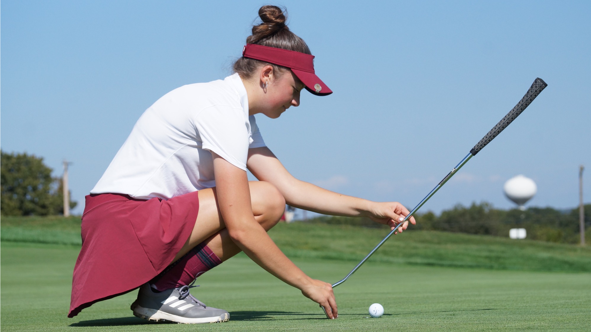 Women's golfer Macy Trostle on the green eyeing up a putt