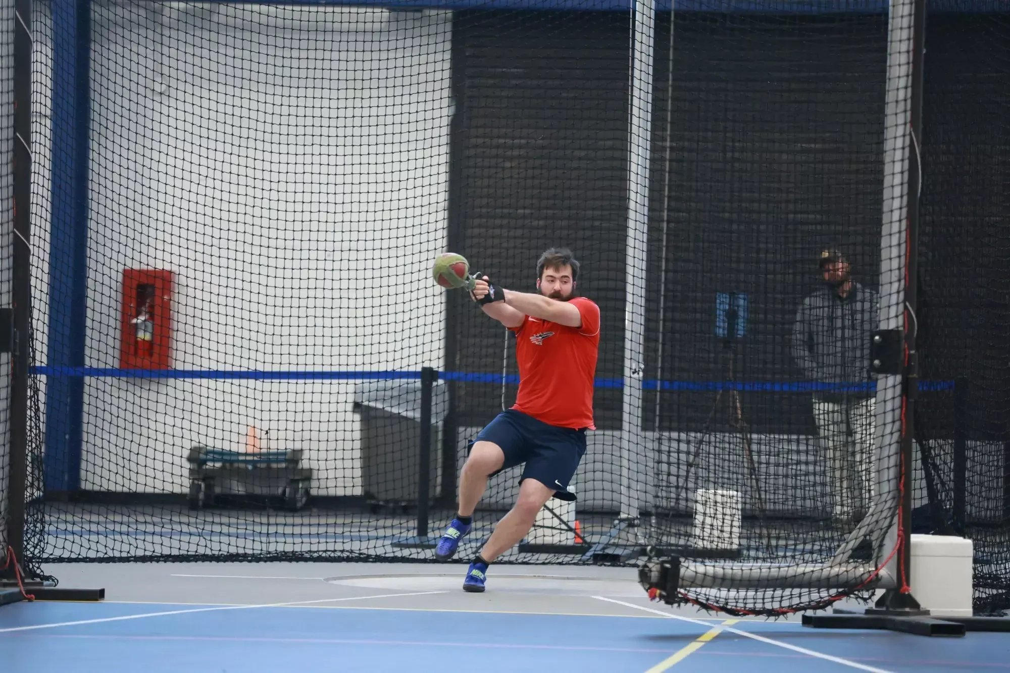 Brandon Simpson participating in the weight throw in an indoor track meet.
