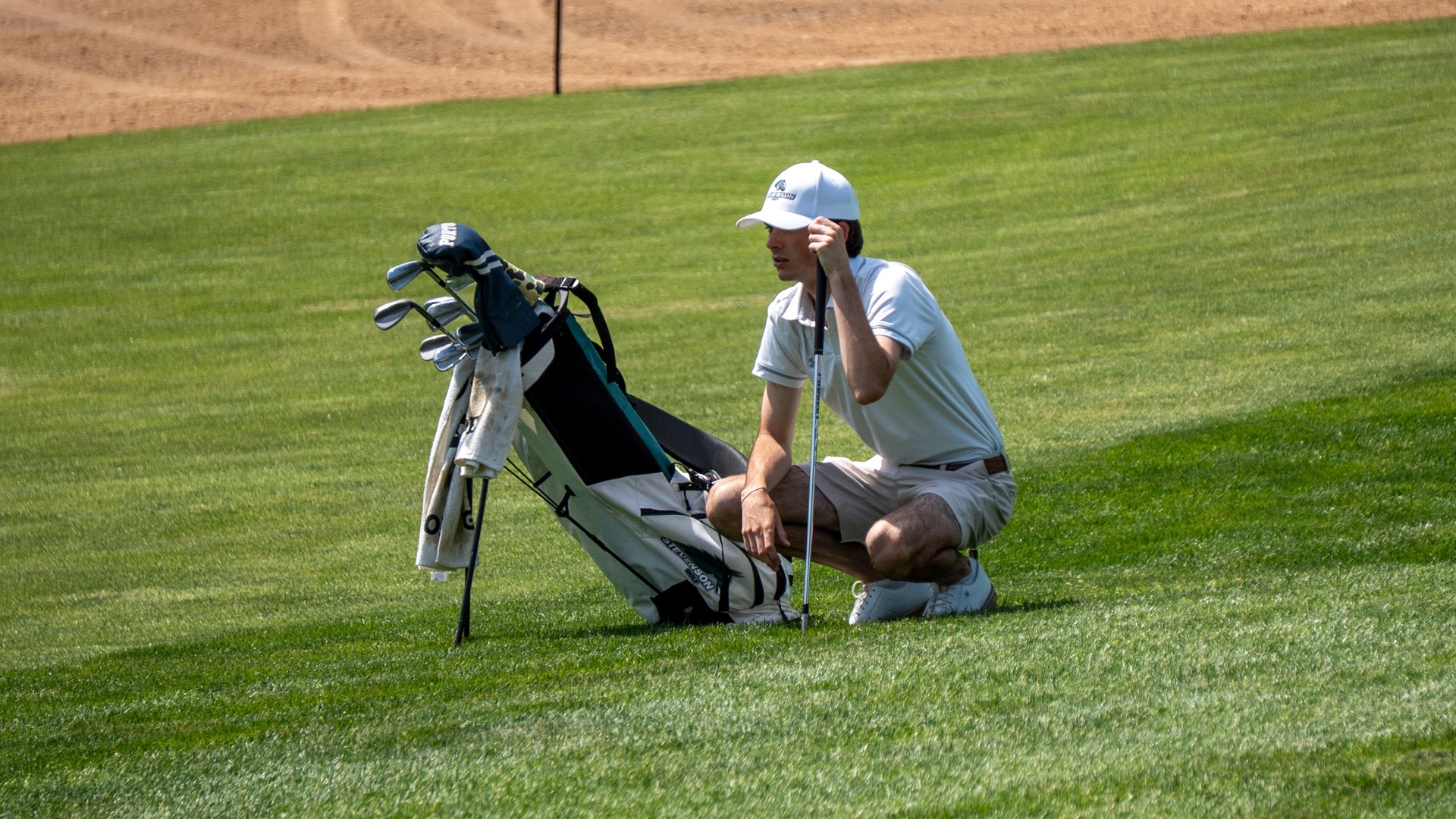 Men's Golf looking on and lining up his shot