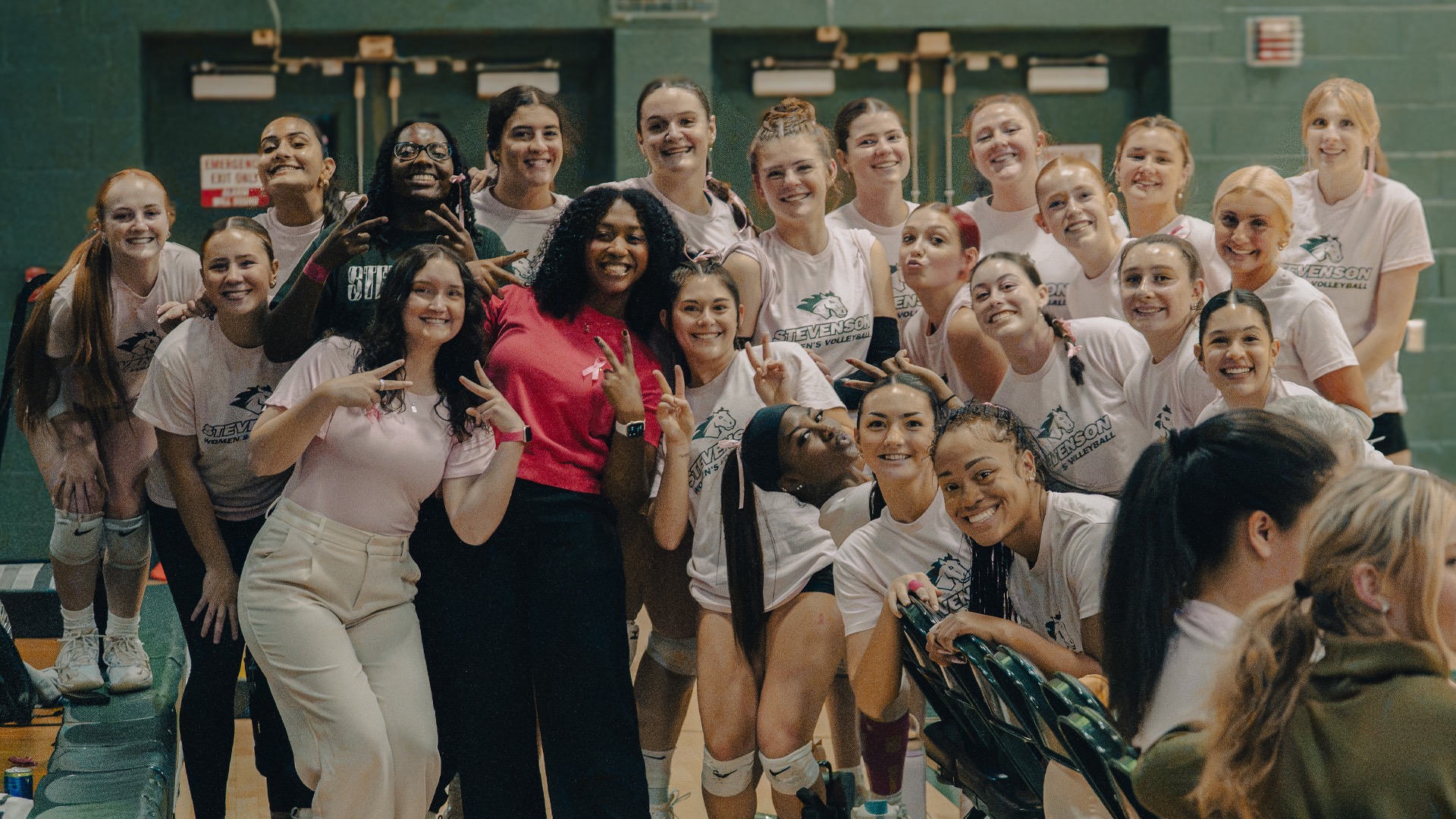 Women's Volleyball Team posing before the Dig Pink Match against Hood