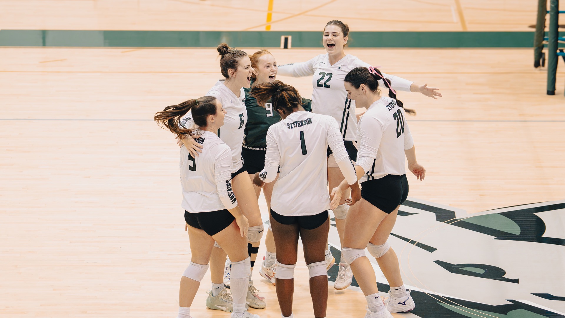Women's Volleyball Celebrating a point won, in a team huddle