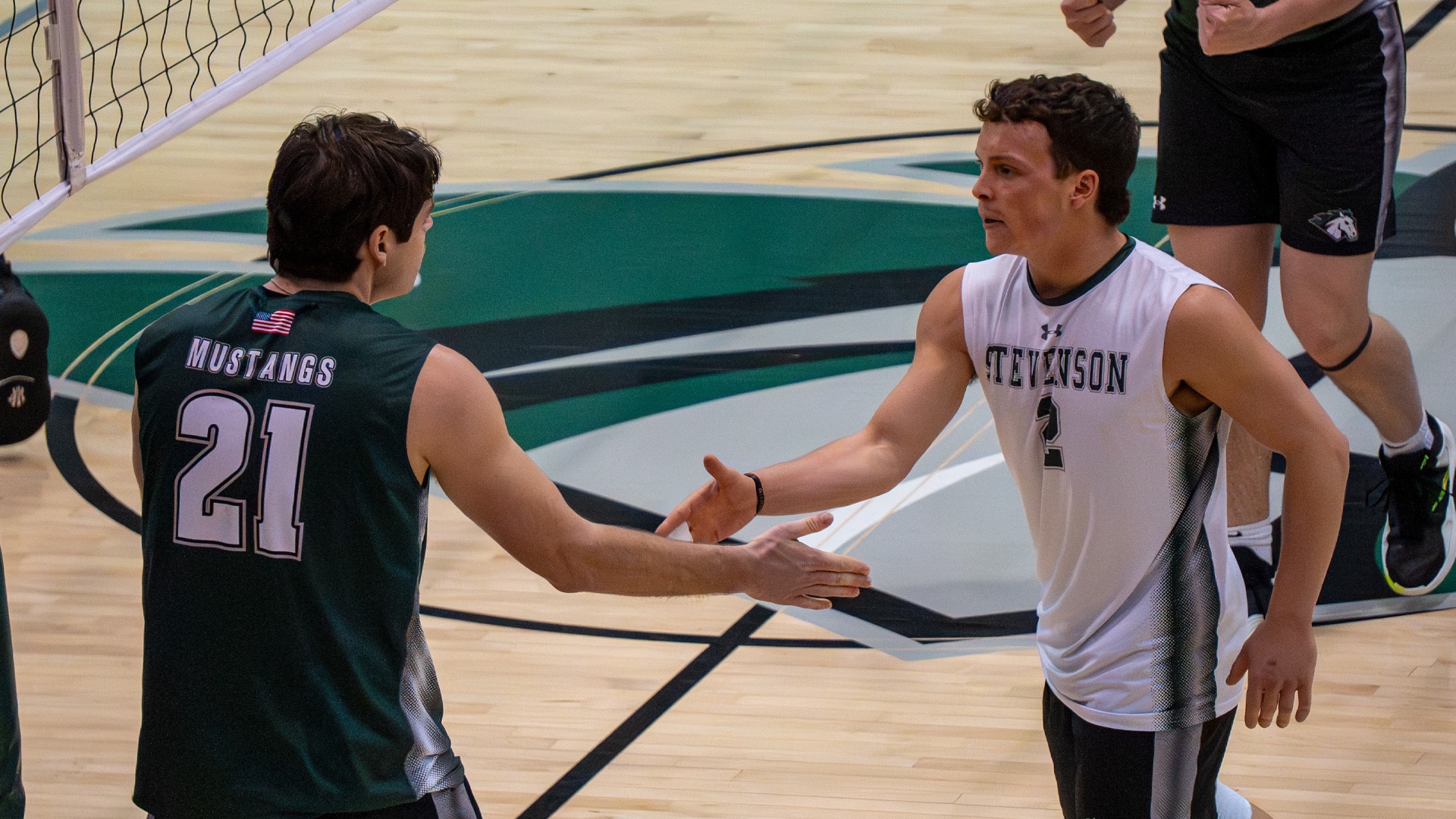 Sarmuksnis and Kouchoukos giving each other a high-five on the sideline of the court