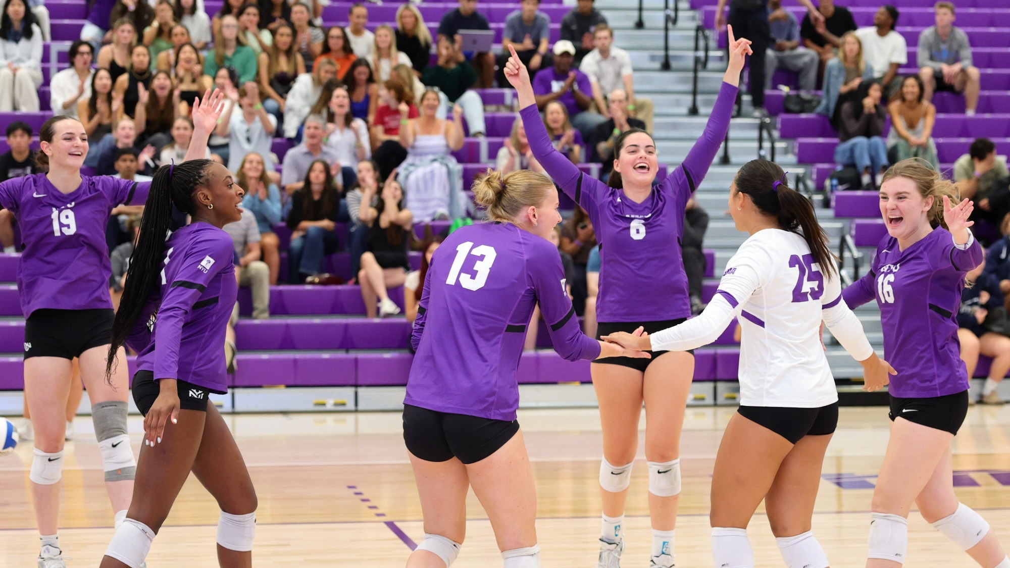 Alden Roberts celebrates with the women's volleyball team after winning a point