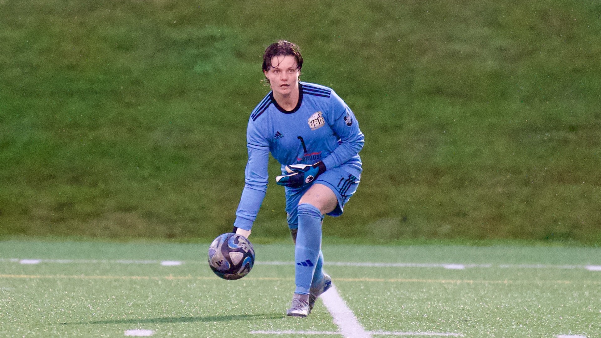 Dakota Beckett rolls the ball towards the camera while crouching down