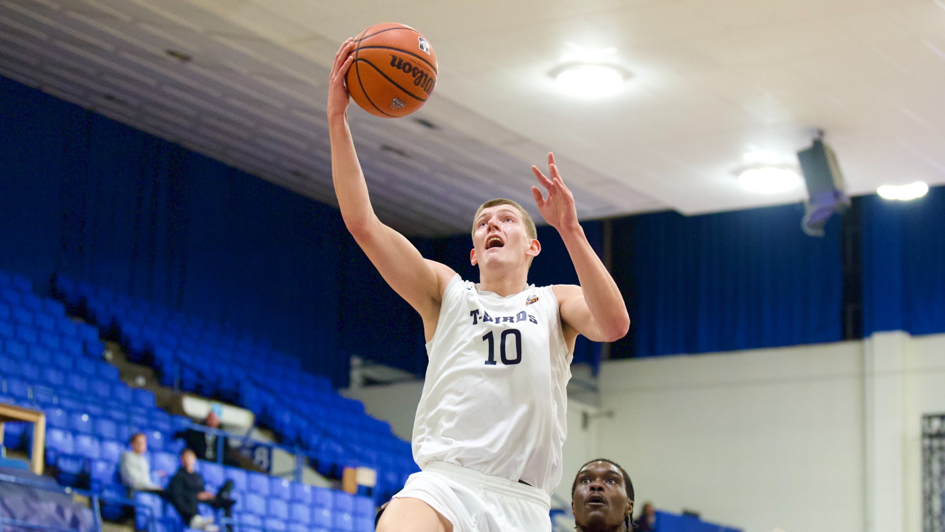 Gus Goerzen soaring high and cupping the ball in his right hand, mouth wide open, as he goes in for a layup