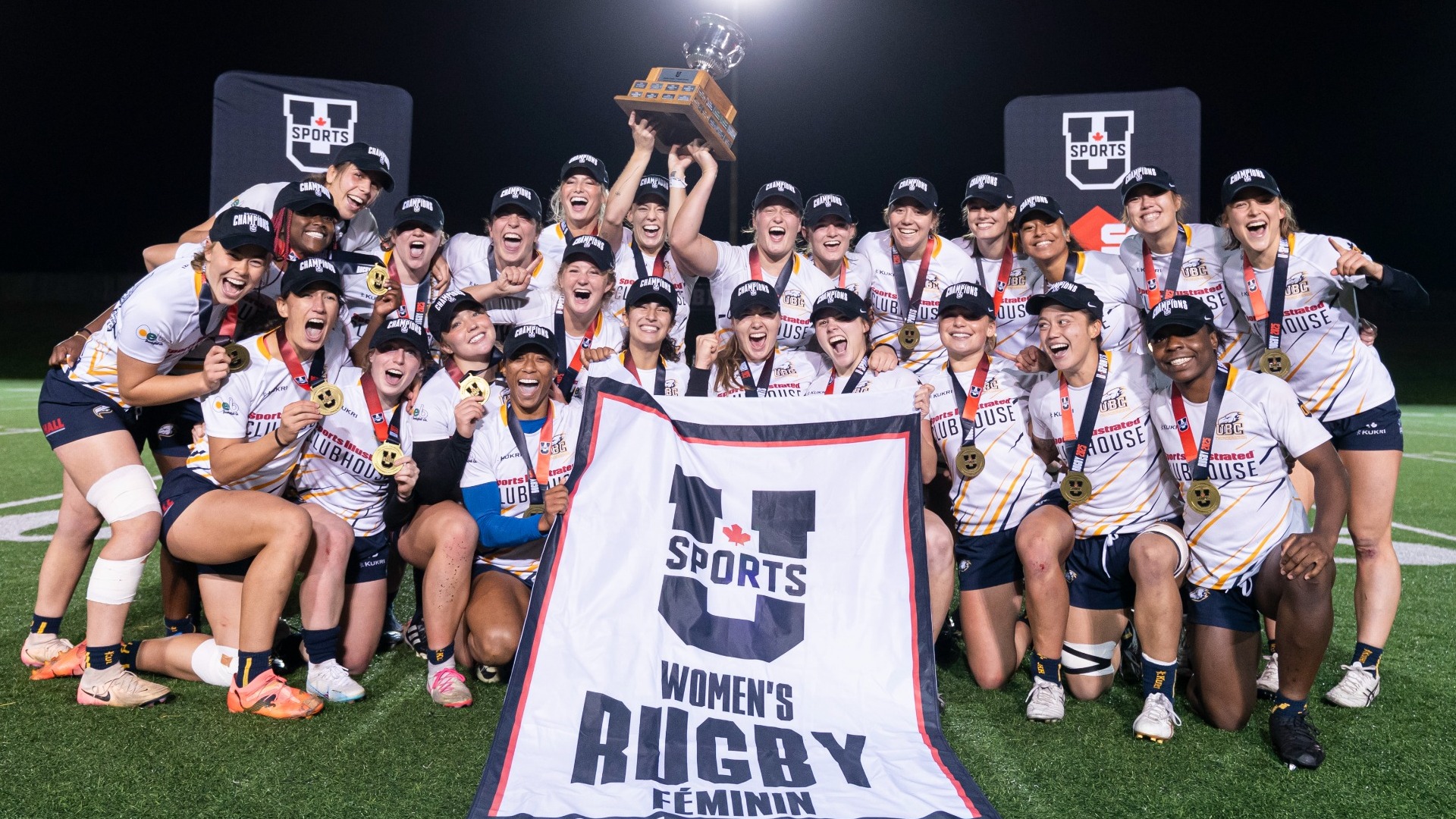The UBC Thunderbirds Women's Rugby Team posing with a banner and trophy after winning the 2025 U SPORTS Championship at home