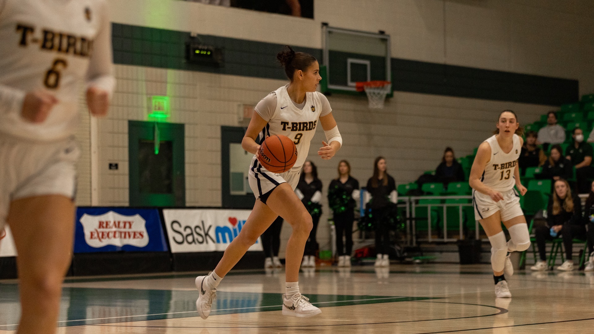 Olivia Weekes dribbles the ball up the court while flanked by a couple teammates